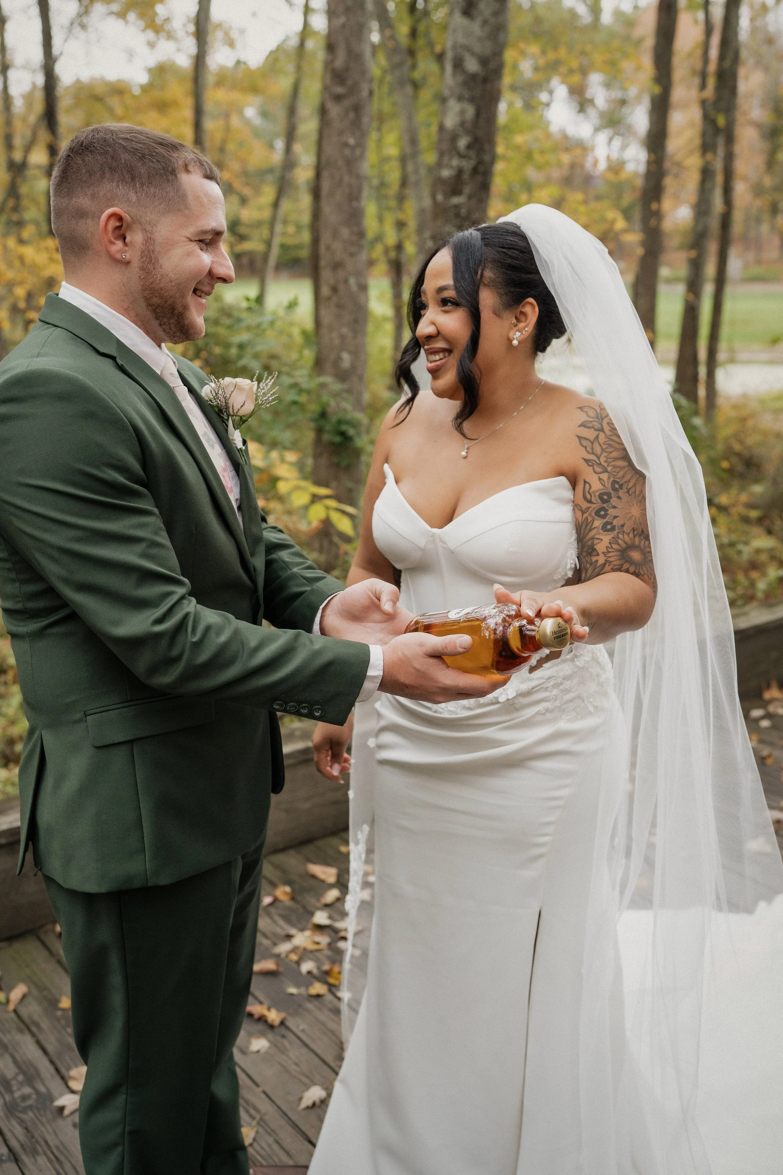 A bride and groom exchanging a gift during their wedding ceremony in an outdoor forest setting.