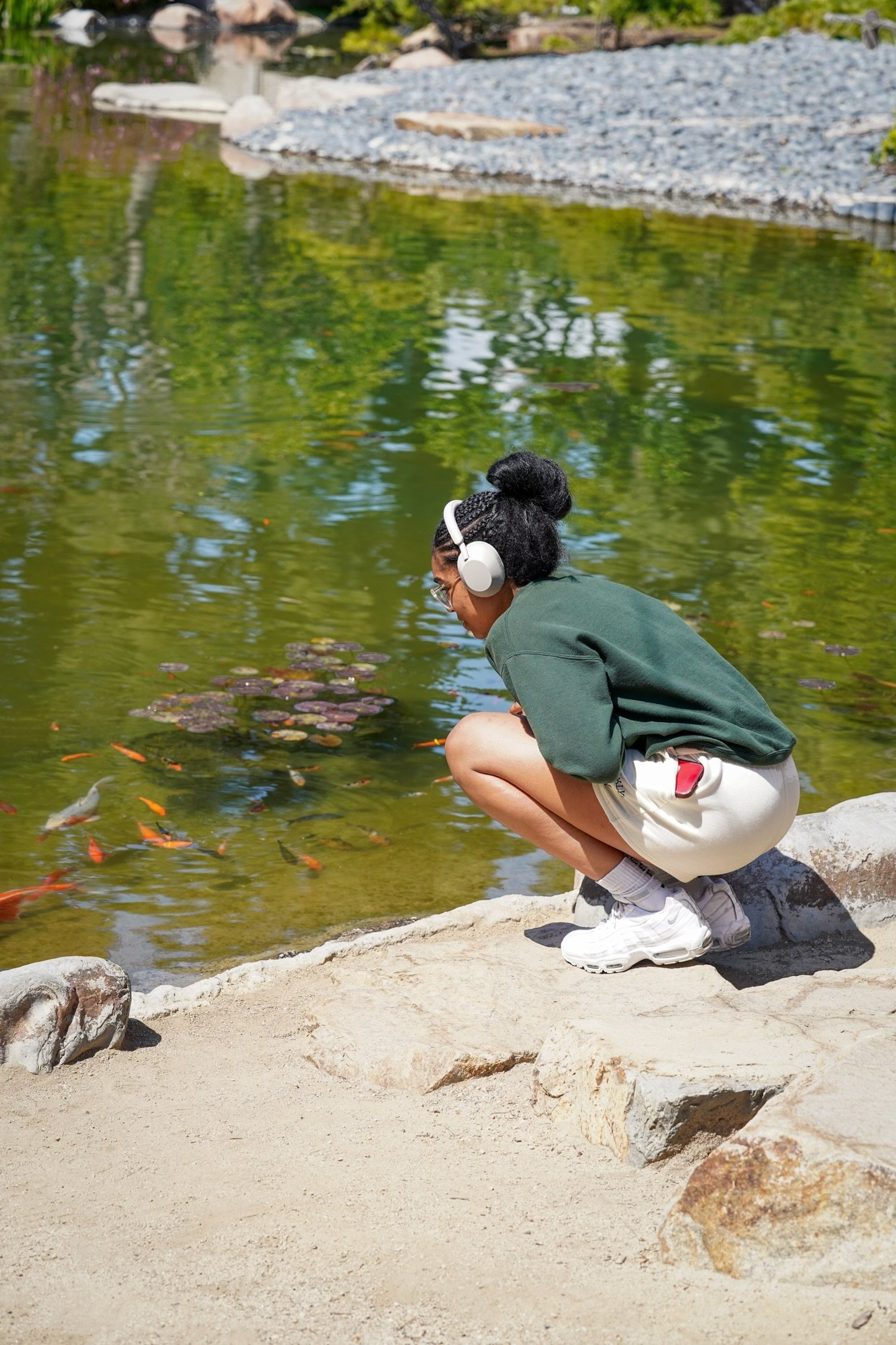  Sydney Woodley crouches at the edge of the pond to observe the baby koi fish. Photo by Kimberly Carrillo 