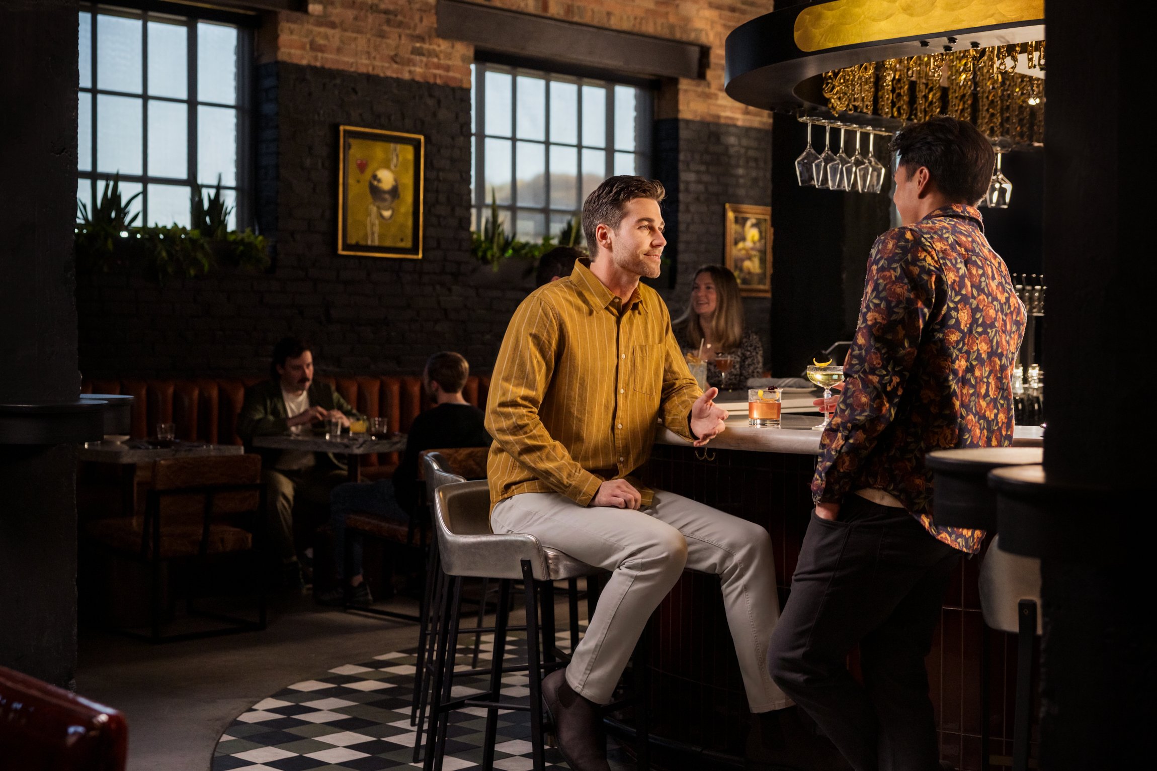 two men speaking at bar