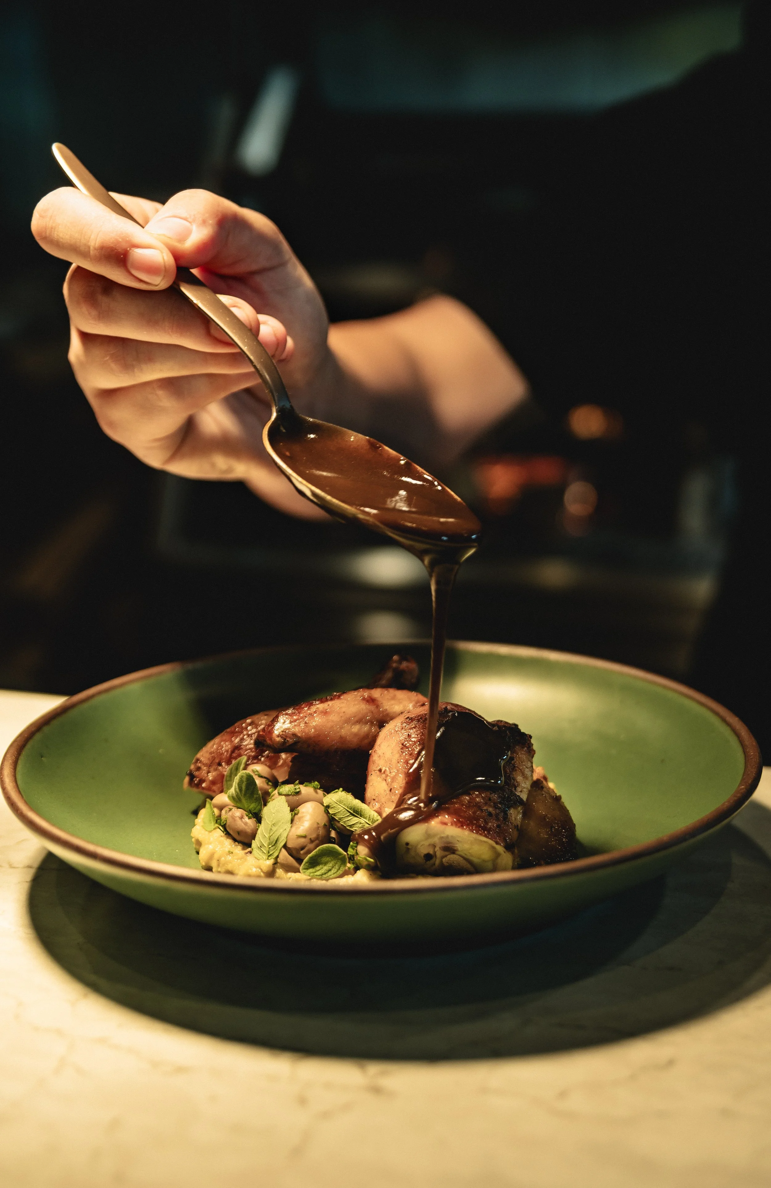 chef drizzling sauce on dish