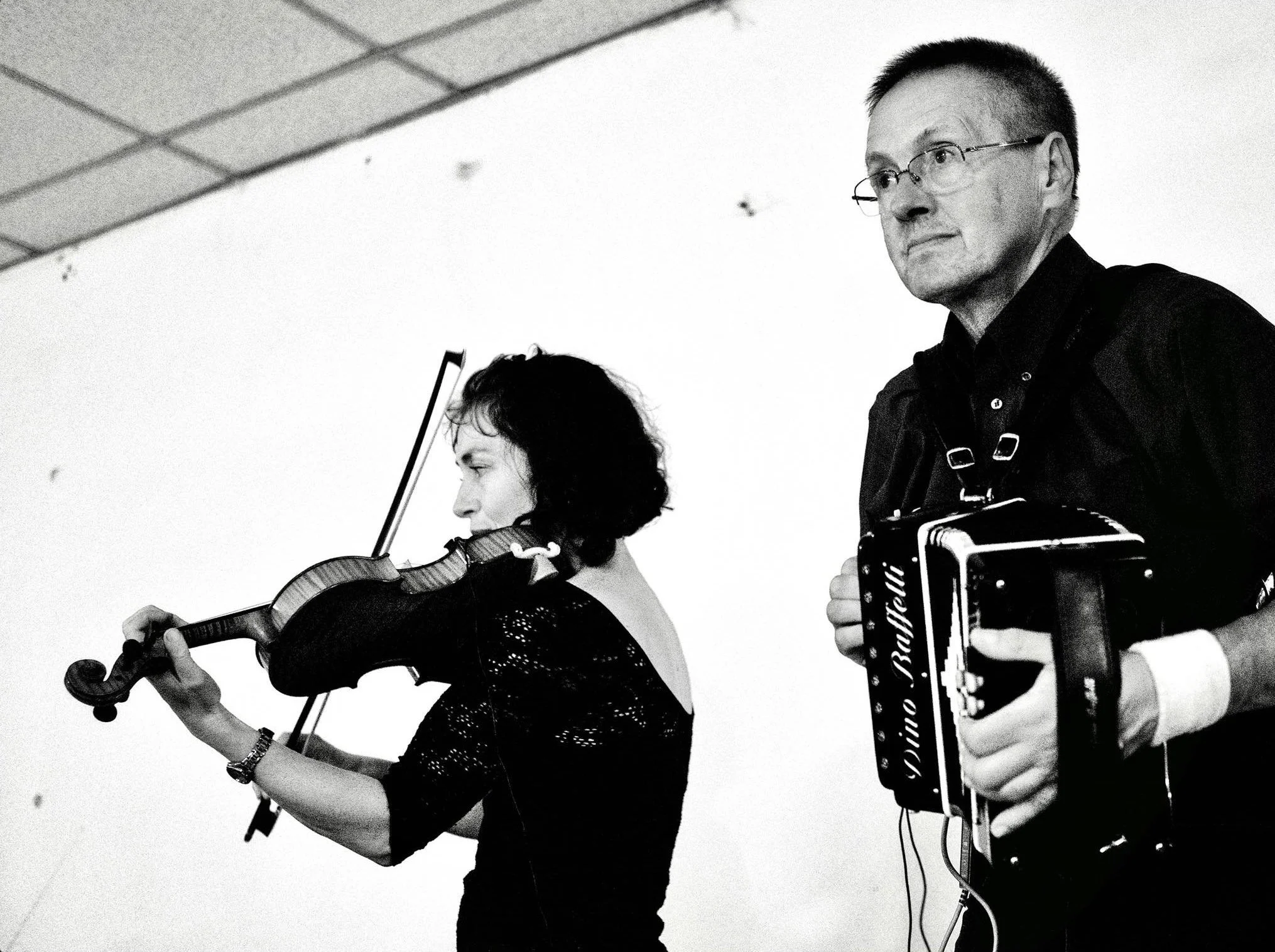 A woman playing a violin and a man playing an accordion during a musical performance.