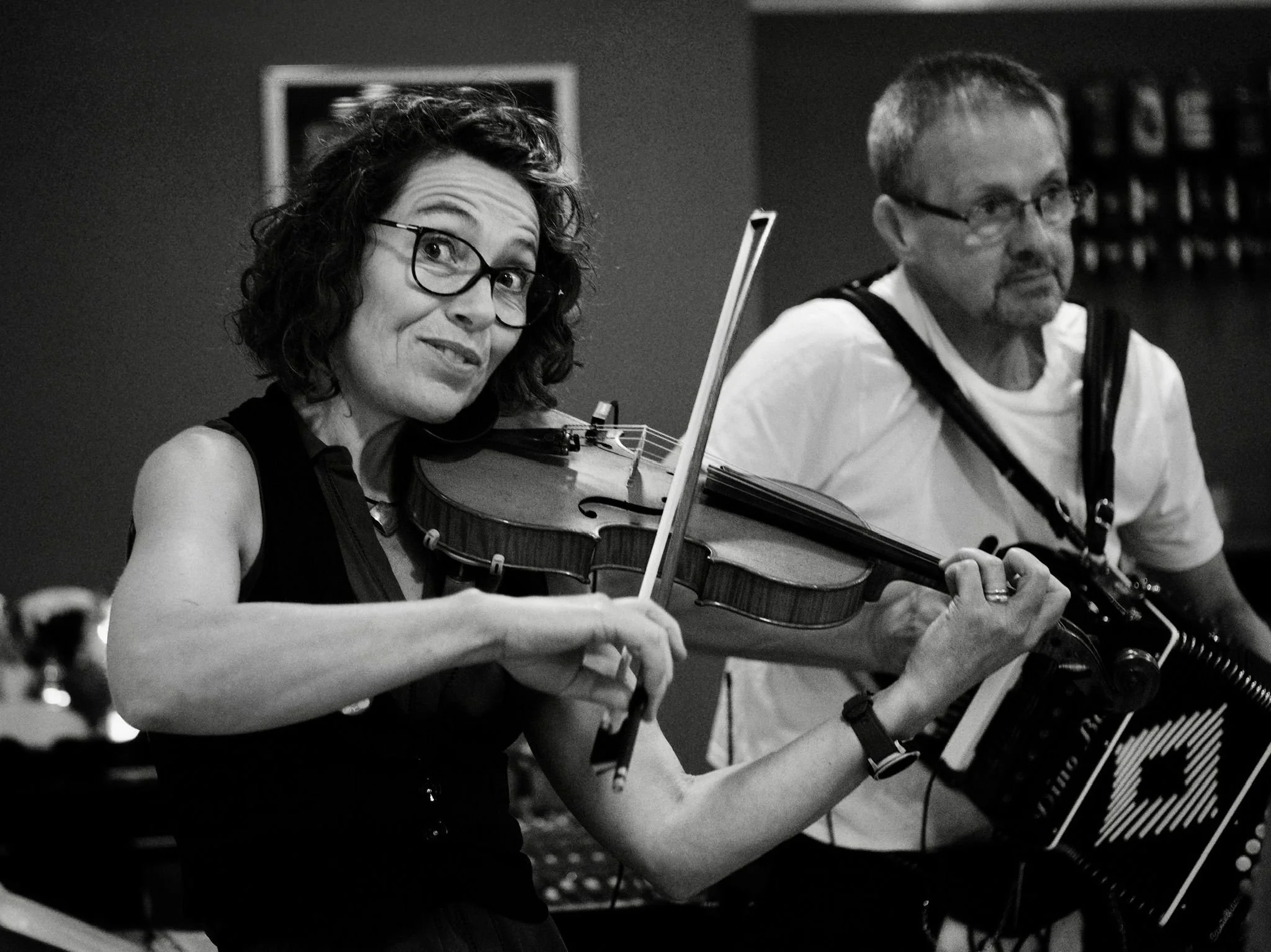 A woman playing a violin and a man playing an accordion.