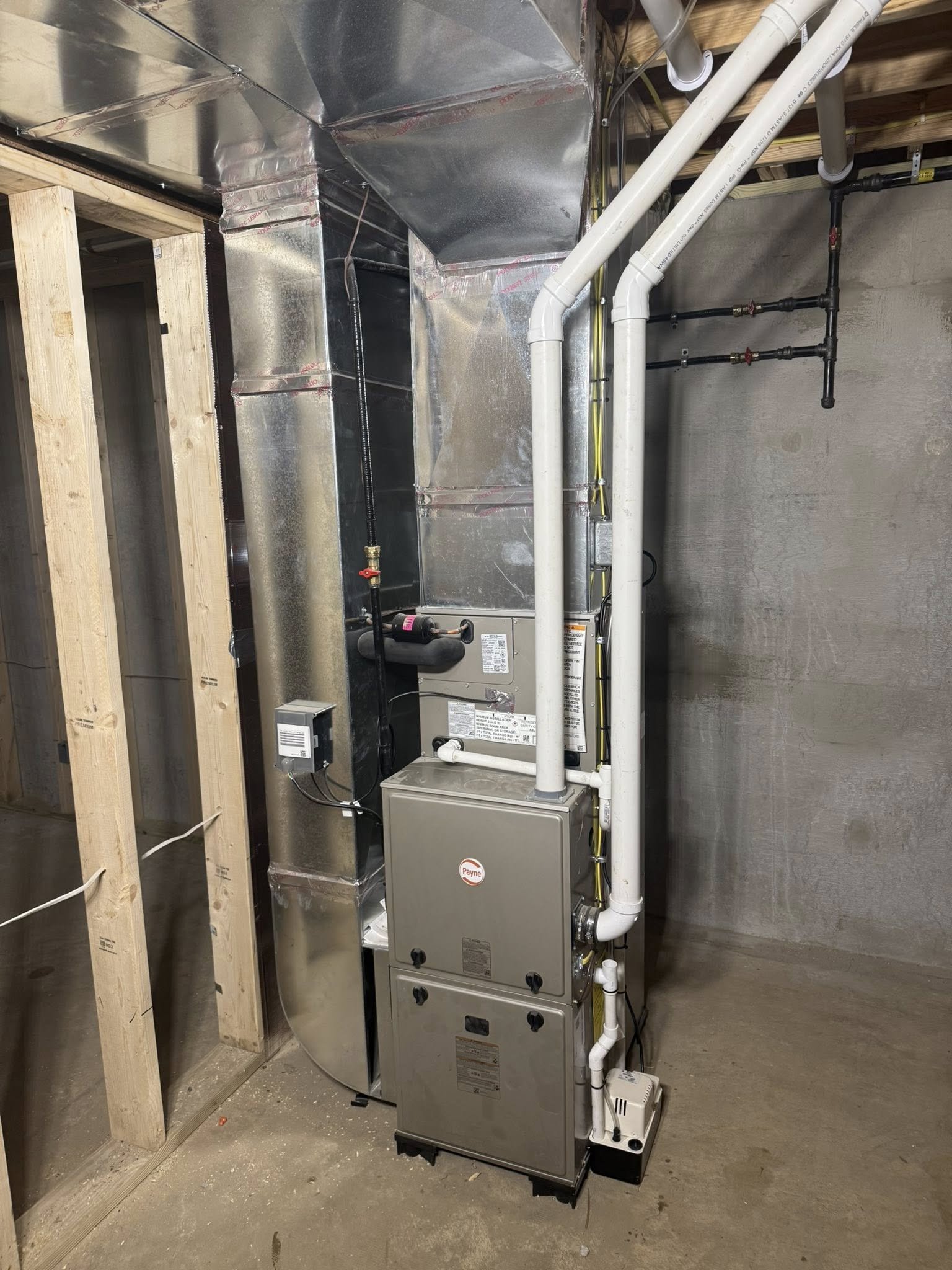 Side of a house showing electrical and HVAC system components; including wiring, a service panel, an air conditioning unit, and utility meters.