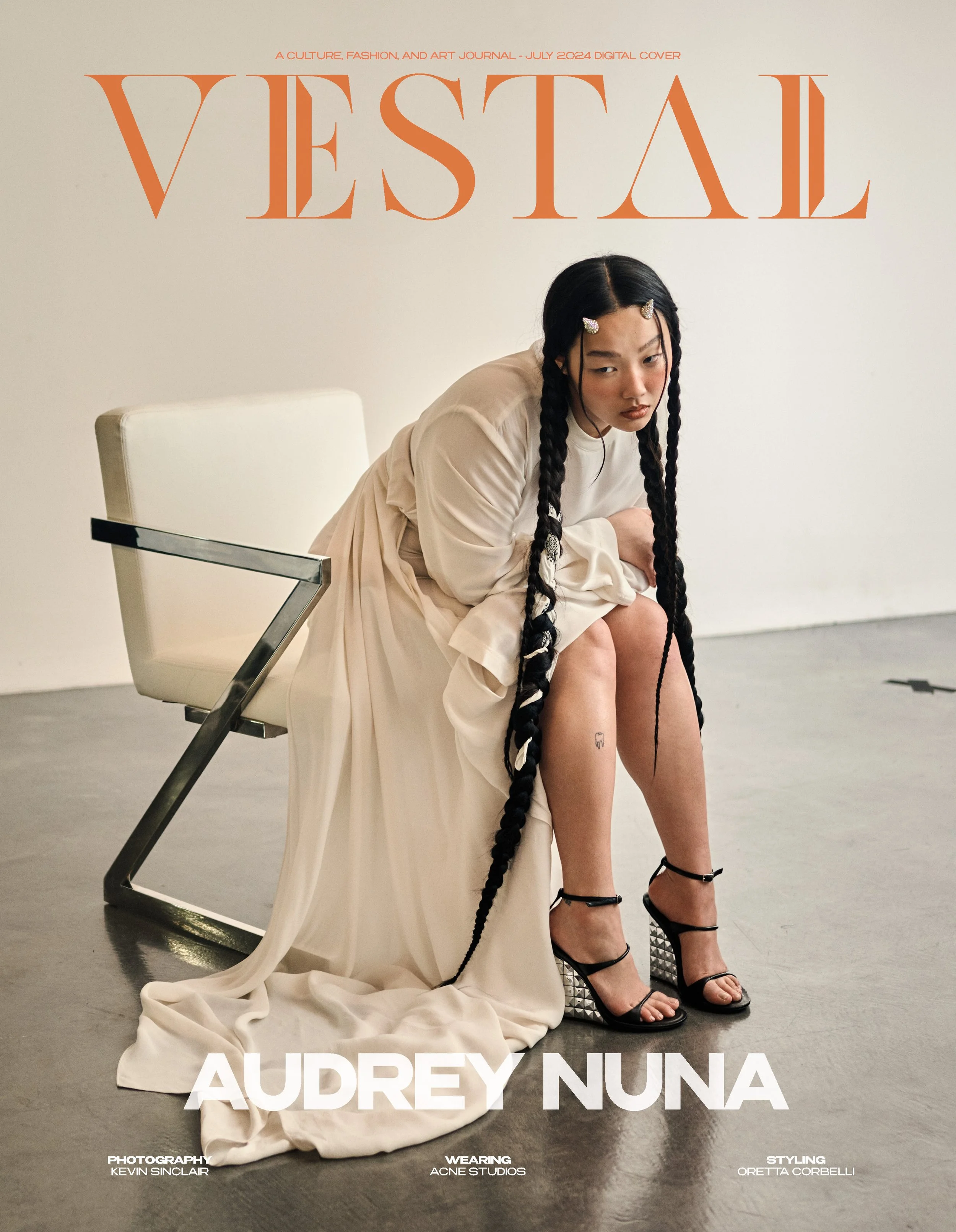 Cover of Vessel magazine featuring Audrey Nuna sitting on a cream-colored chair, wearing a long cream dress and black high-heeled shoes with silver spikes, with long braided hair and a contemplative expression.