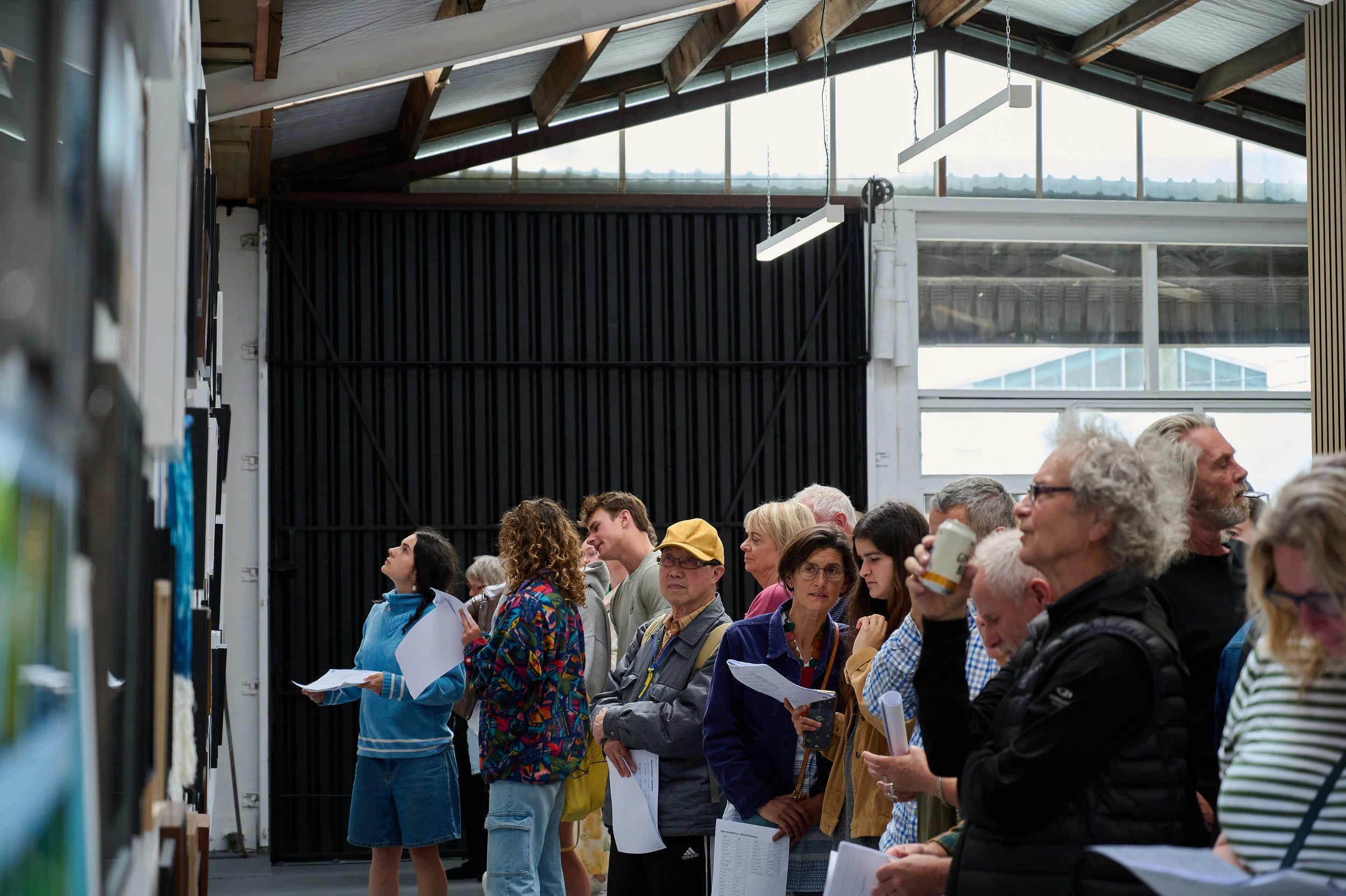 Visitors closely viewing artworks at a Photosynthesis exhibition opening in Christchurch.