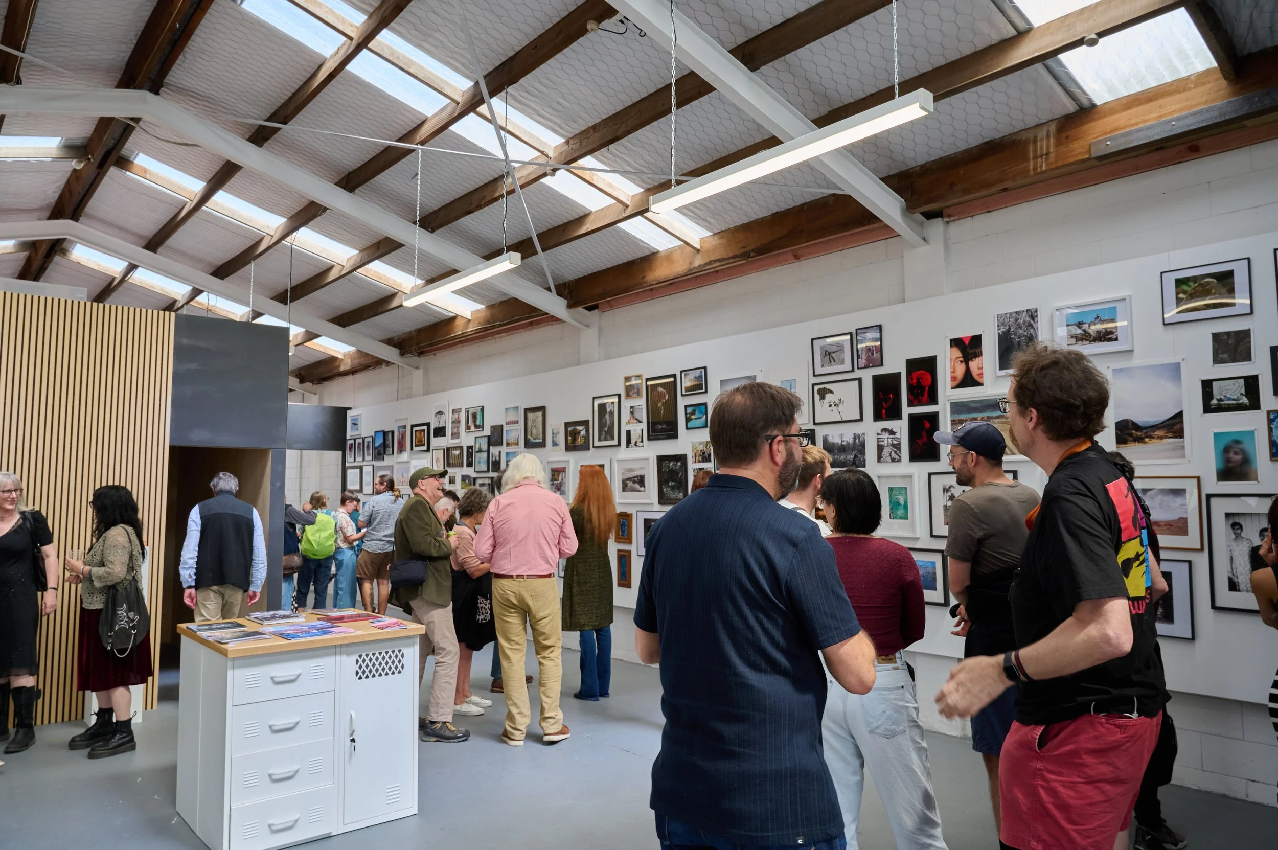 Visitors viewing a wall of photographs at a Photosynthesis exhibition opening in Christchurch.