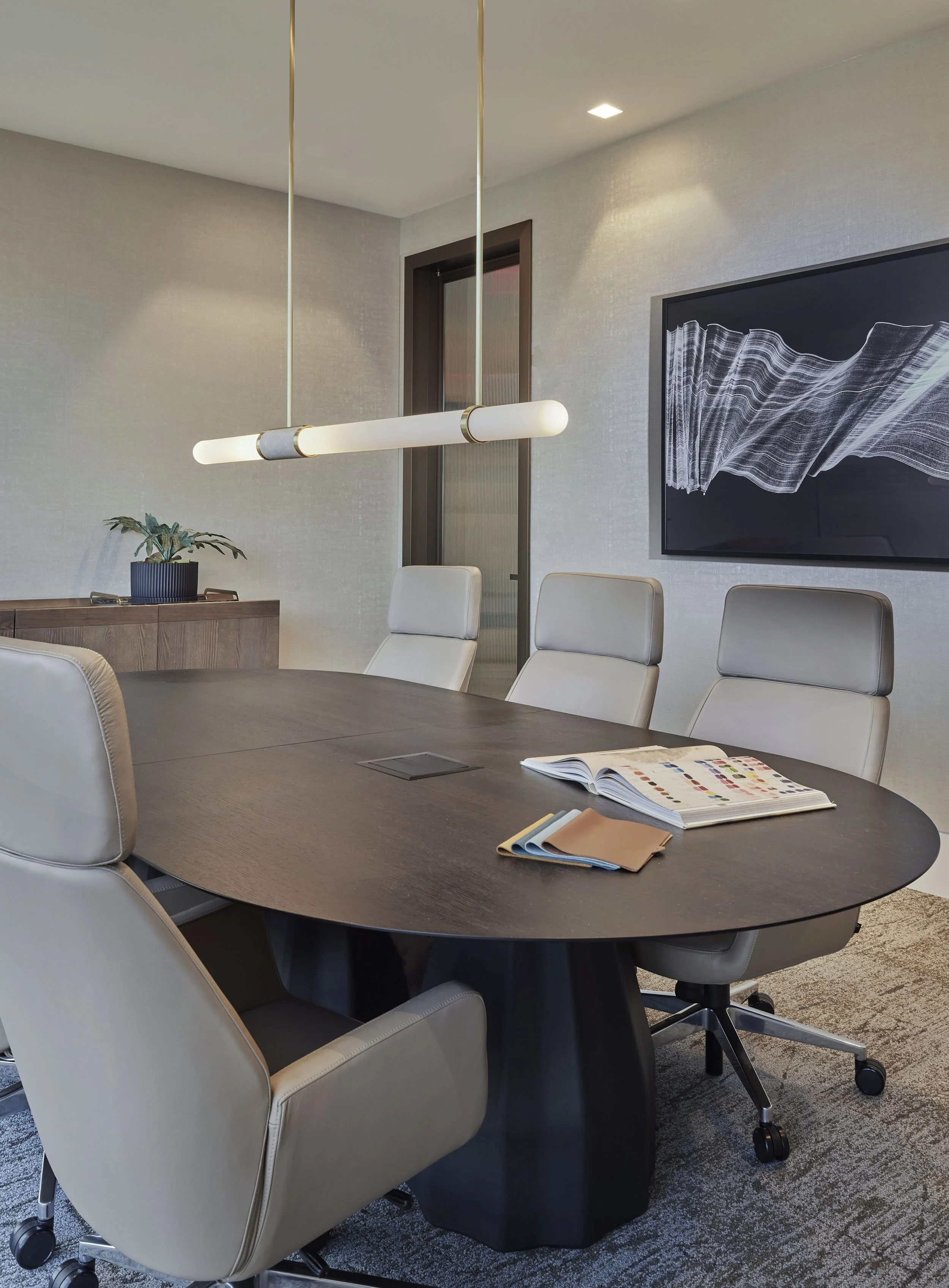 Executive conference room with leather chairs, wood table, and leather wrapped pendant