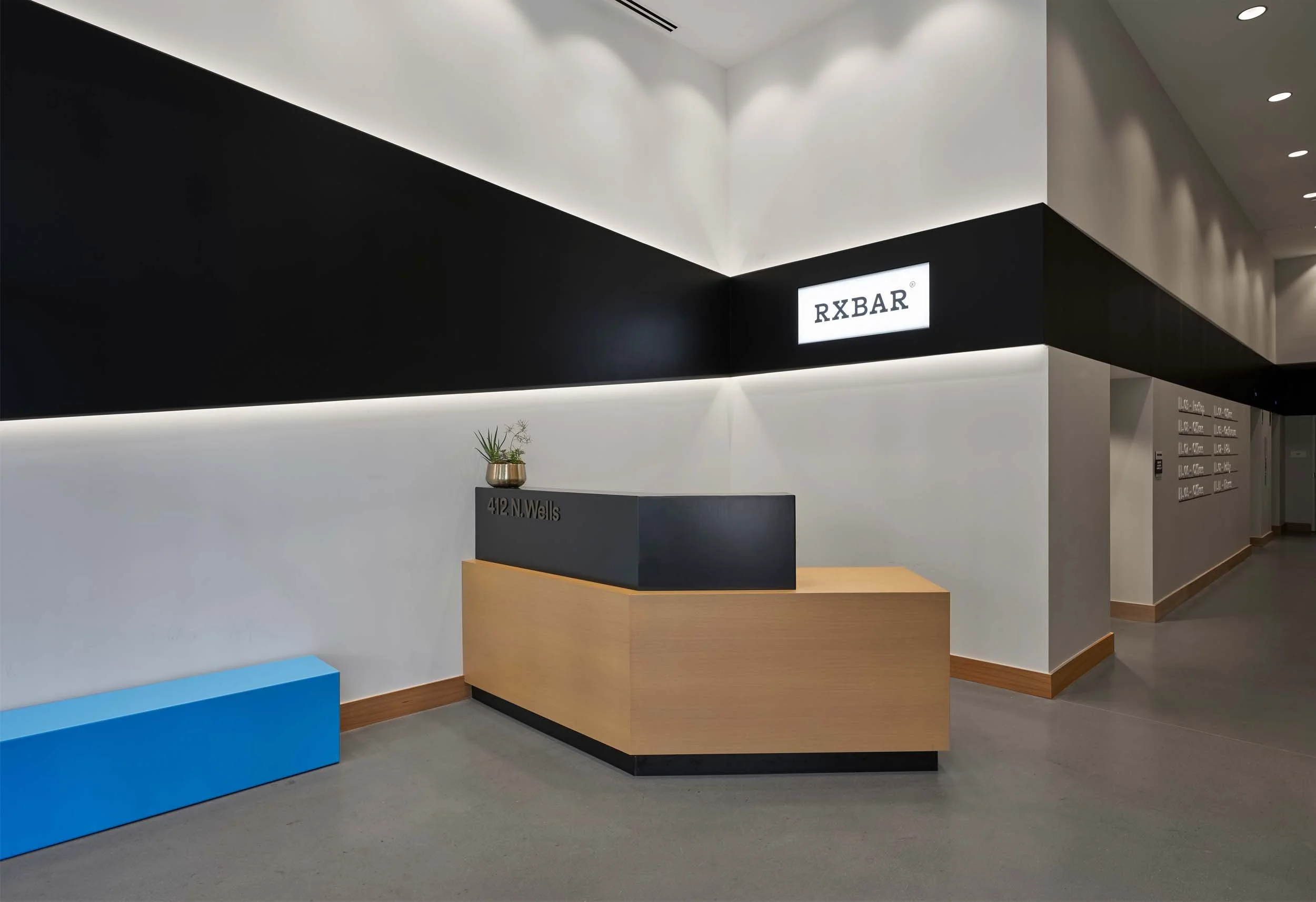 RXBAR lobby with black stripe, powdercoated bench, and illuminated signage