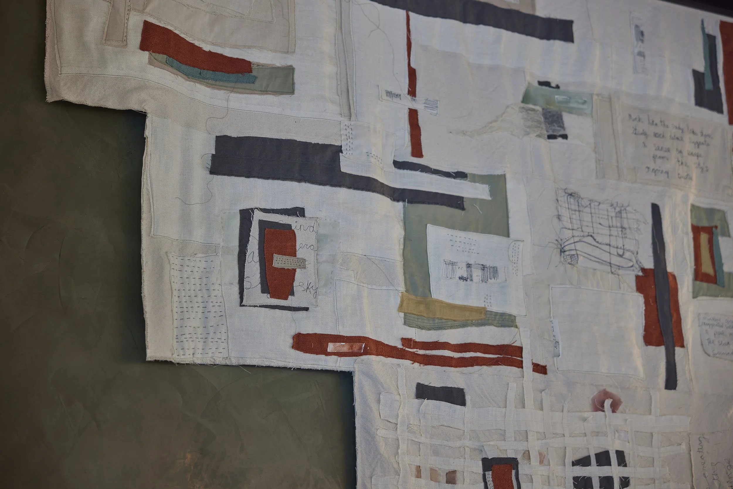 Custom textile art with imagery and stitched words relating to the design concept