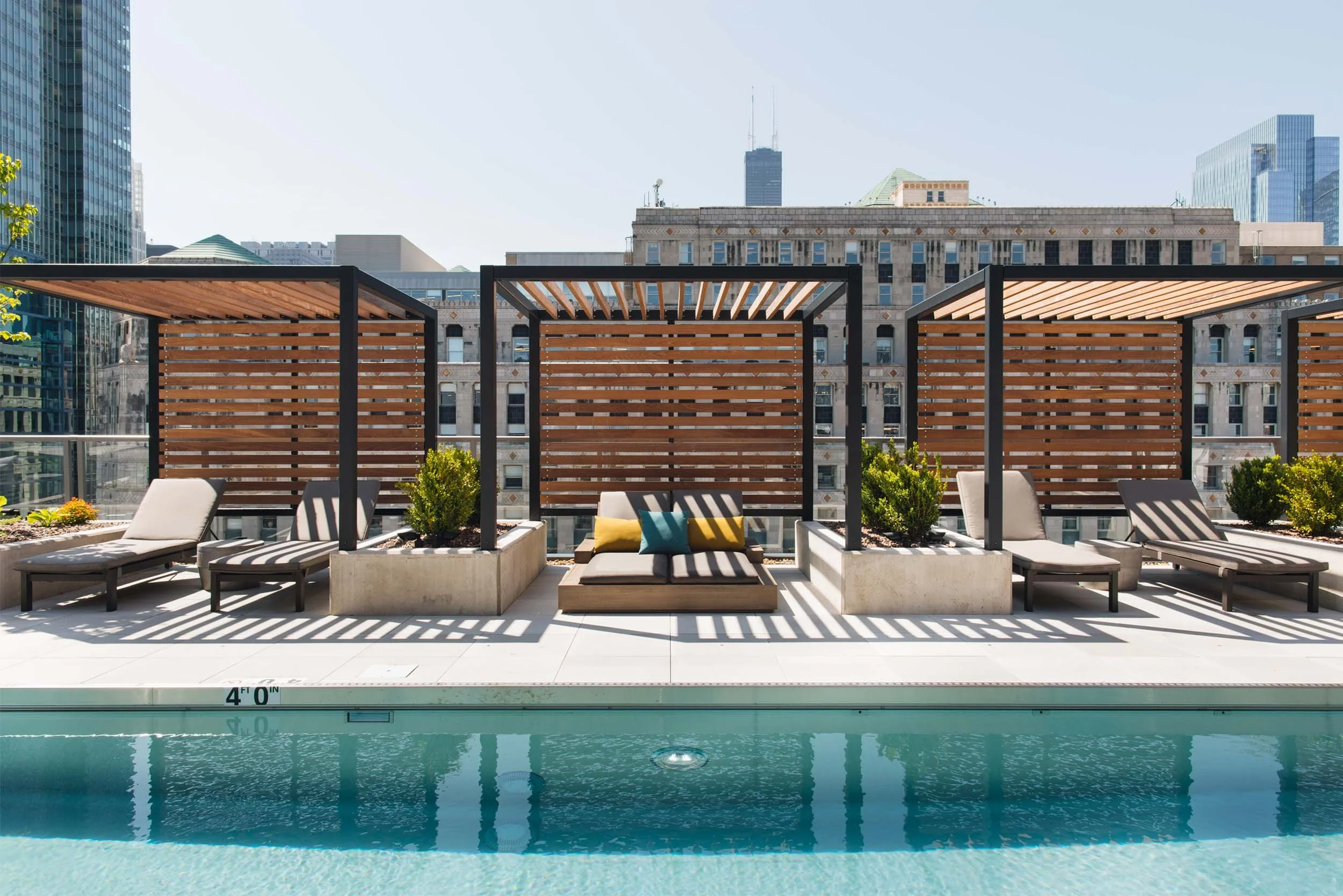 Sun loungers in teak pergolas on city rooftop pool deck