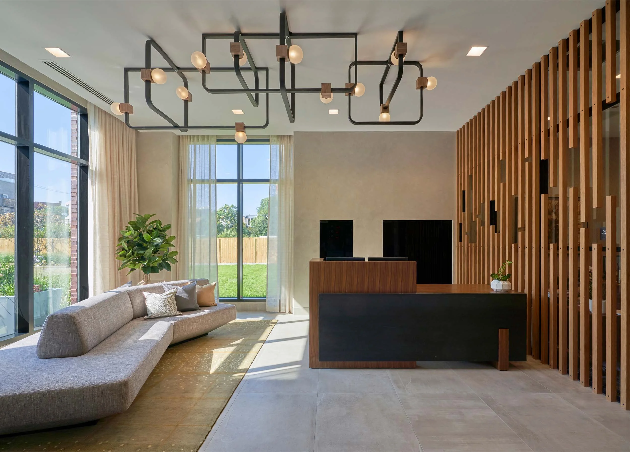 Luxury lobby with custom light fixture, walnut desk, slat wall.