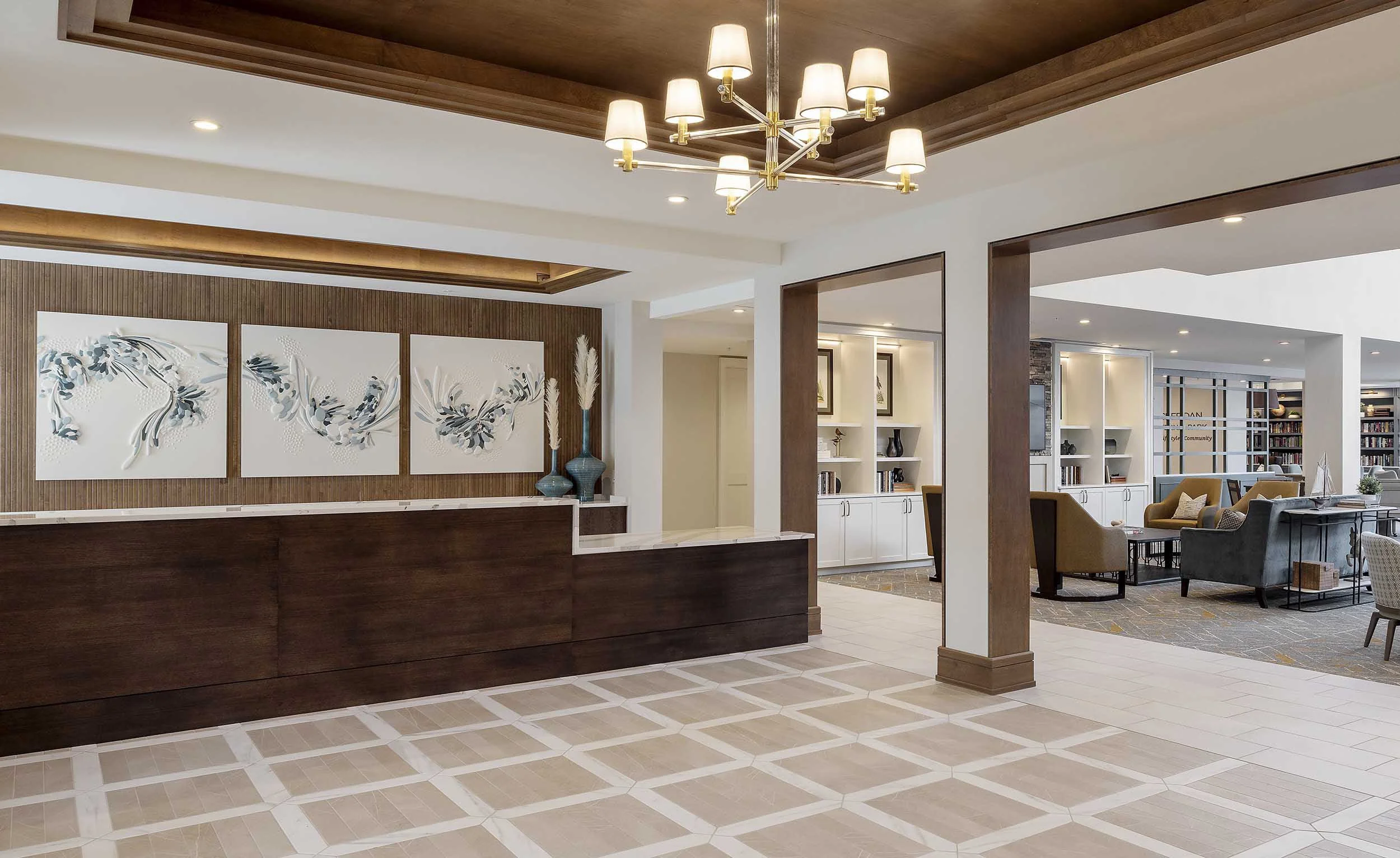 Walnut reception desk, dimensional art, and patterned tile floor at Sheridan at Severna Park