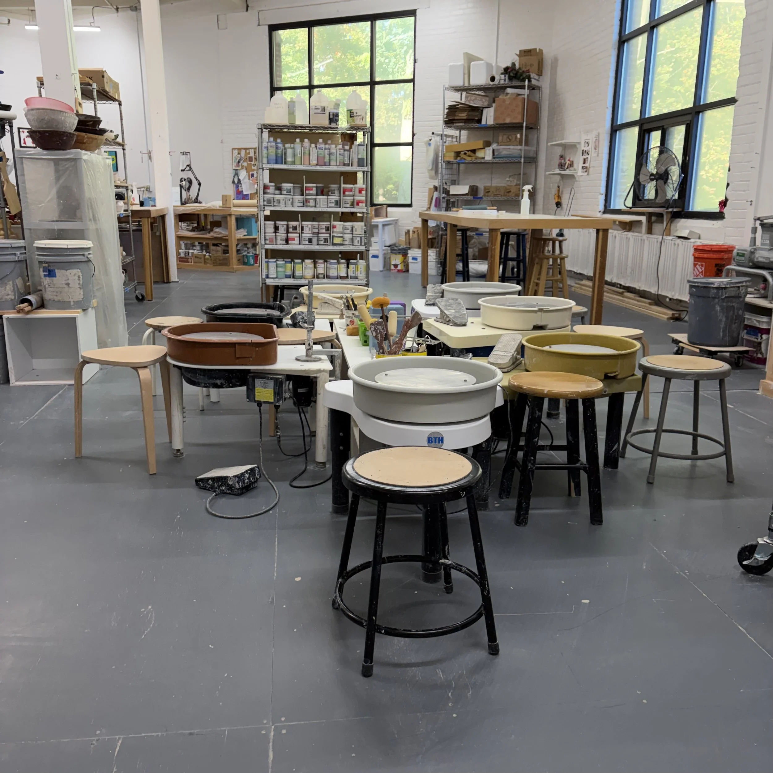 7 electric pottery wheels with bright windows in the background