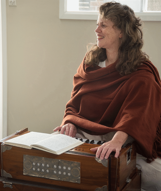 Jacqui Fletcher seated beside a harmonium