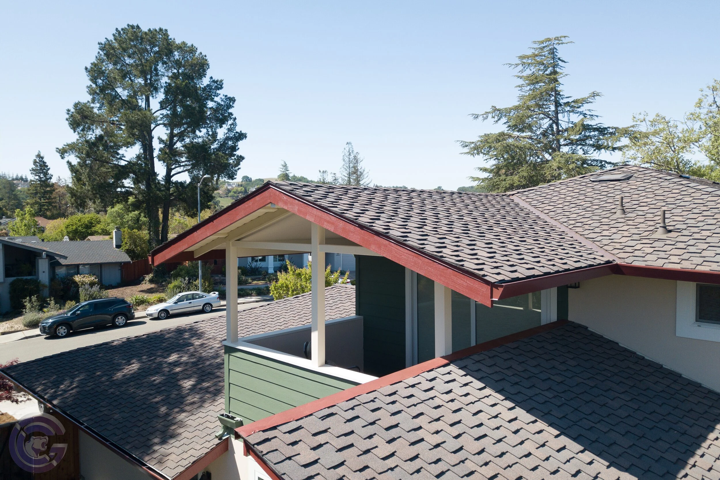 A residential neighborhood with houses, trees, and parked cars under a clear blue sky.