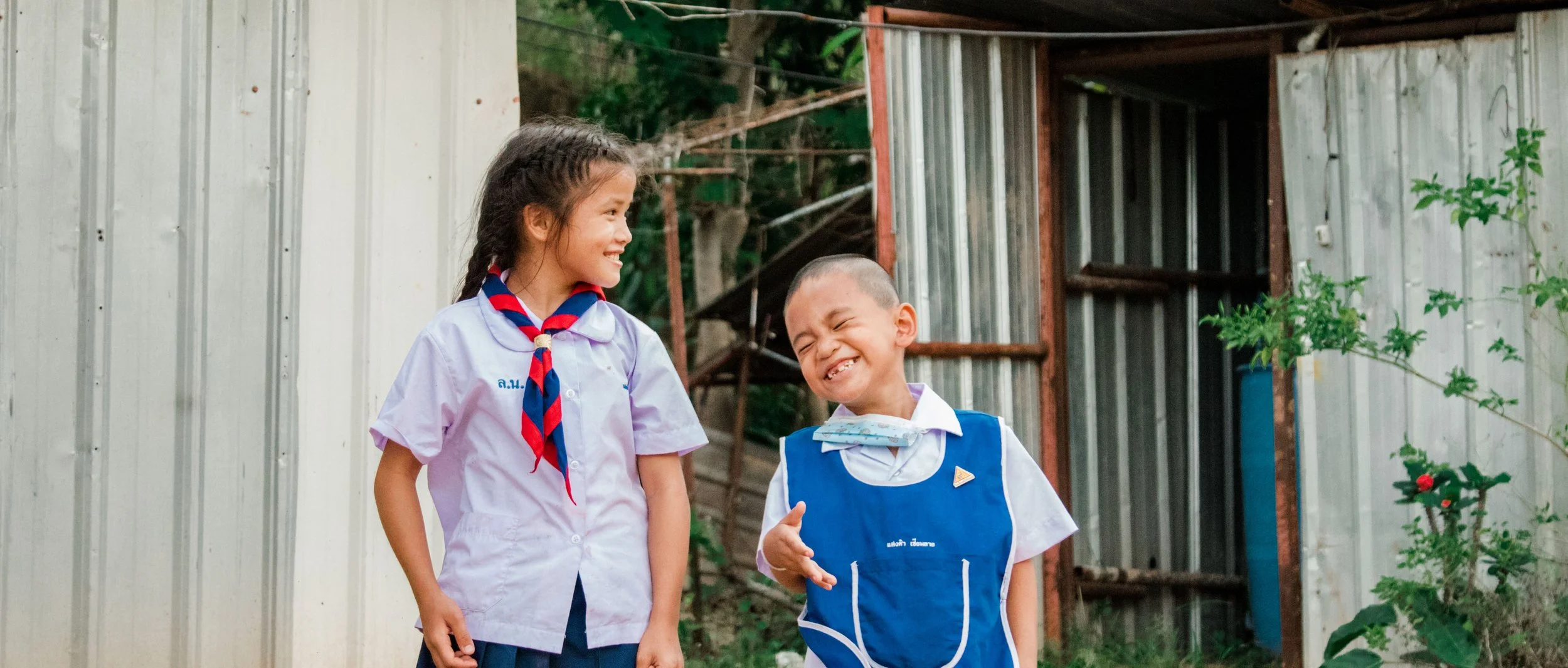 Two young children, girl and boy, looking up at the camera with happy expressions.