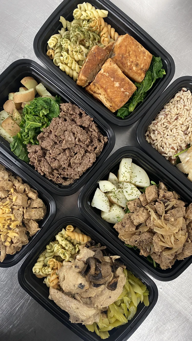 Four meal prep containers with pasta, grilled salmon, ground beef, potatoes and vegetables