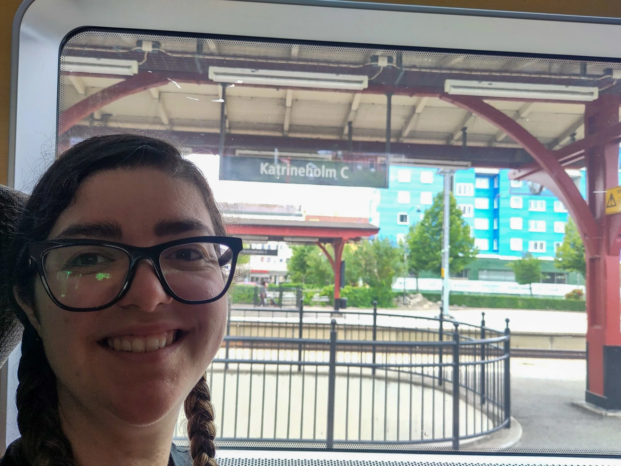 Katrina sat in a train with the station sign outside saying 'Katrineholm'