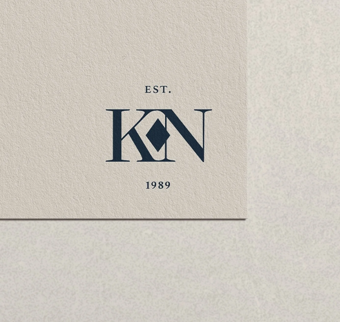 A piece of paper with a logo showcasing branding project featuring the letters 'K' and 'N' intertwined, the word 'EST.' above, and the year '1989' below.