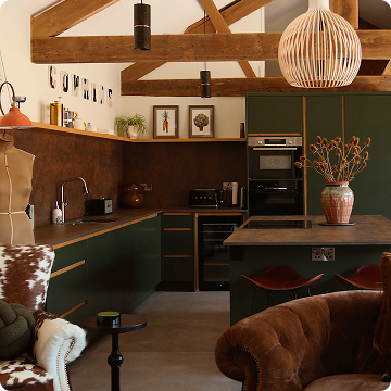 A kitchen with a vintage oven, decorative tiles, a large clock, a wooden shelf, and various kitchen items including a large vase, a spoon, and a plate of pastries.