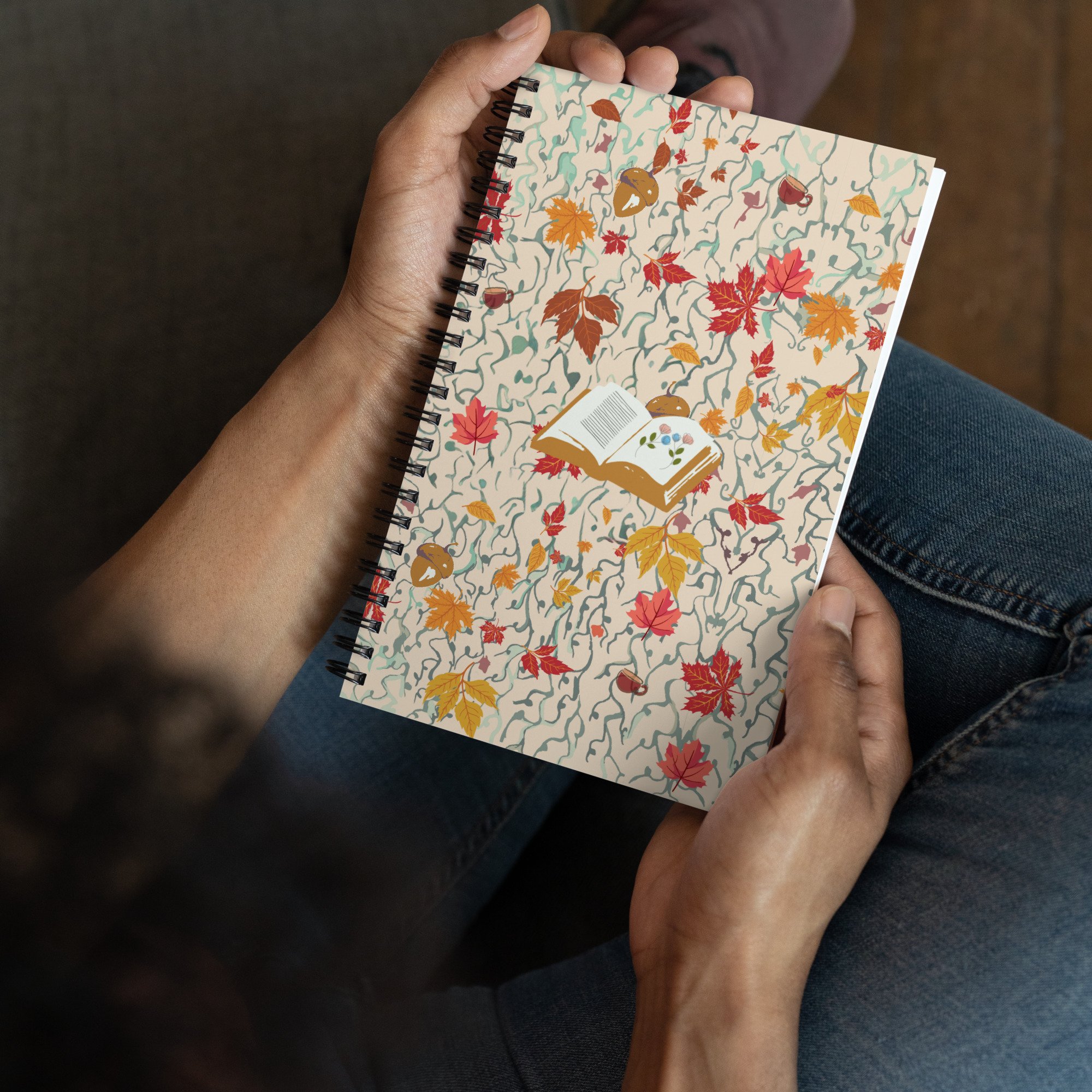 Hands holding the 'It's Writing Season' bullet journal with autumn leaves and open book cover