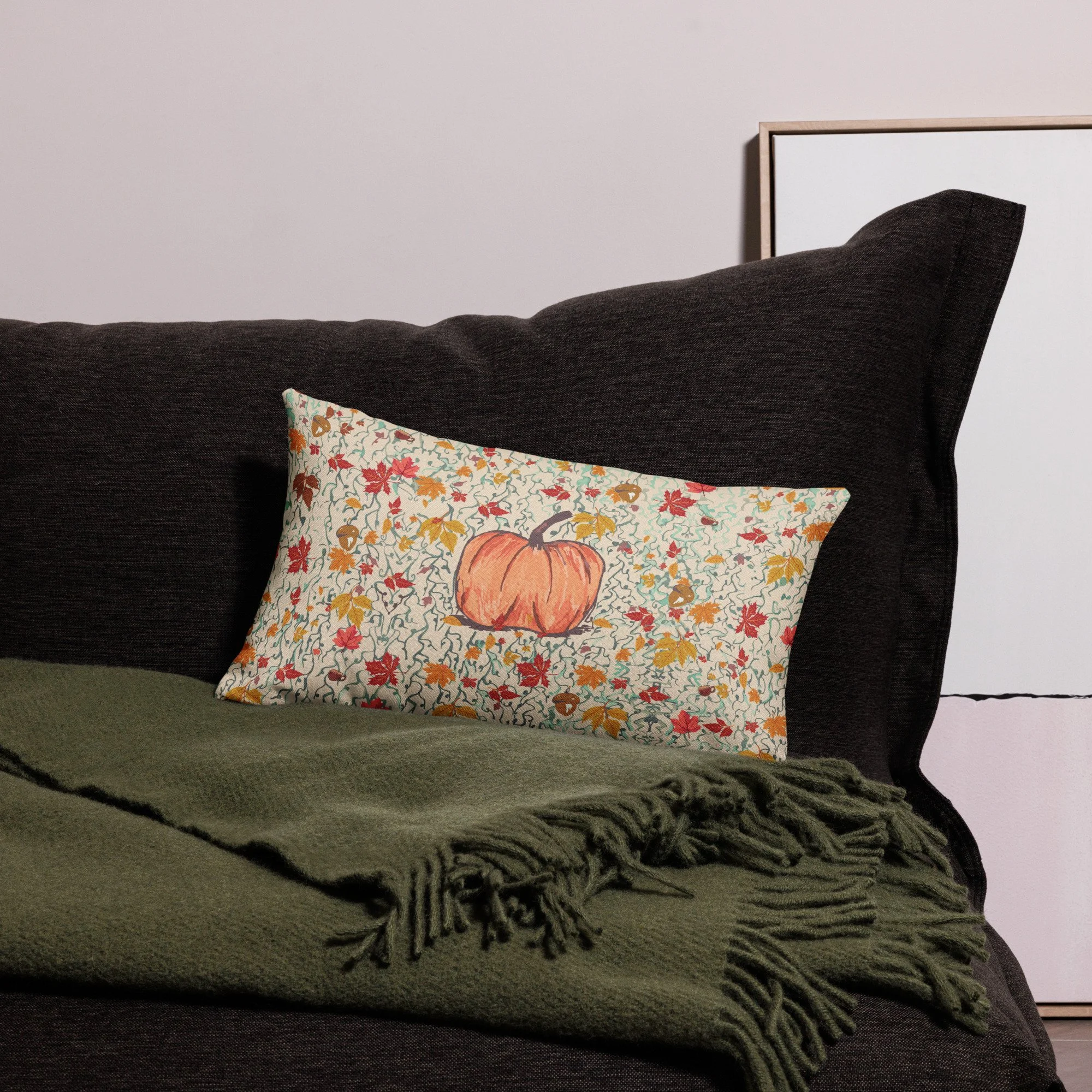 Pumpkin autumn leaf lumbar cushion on a dark sofa with a green throw