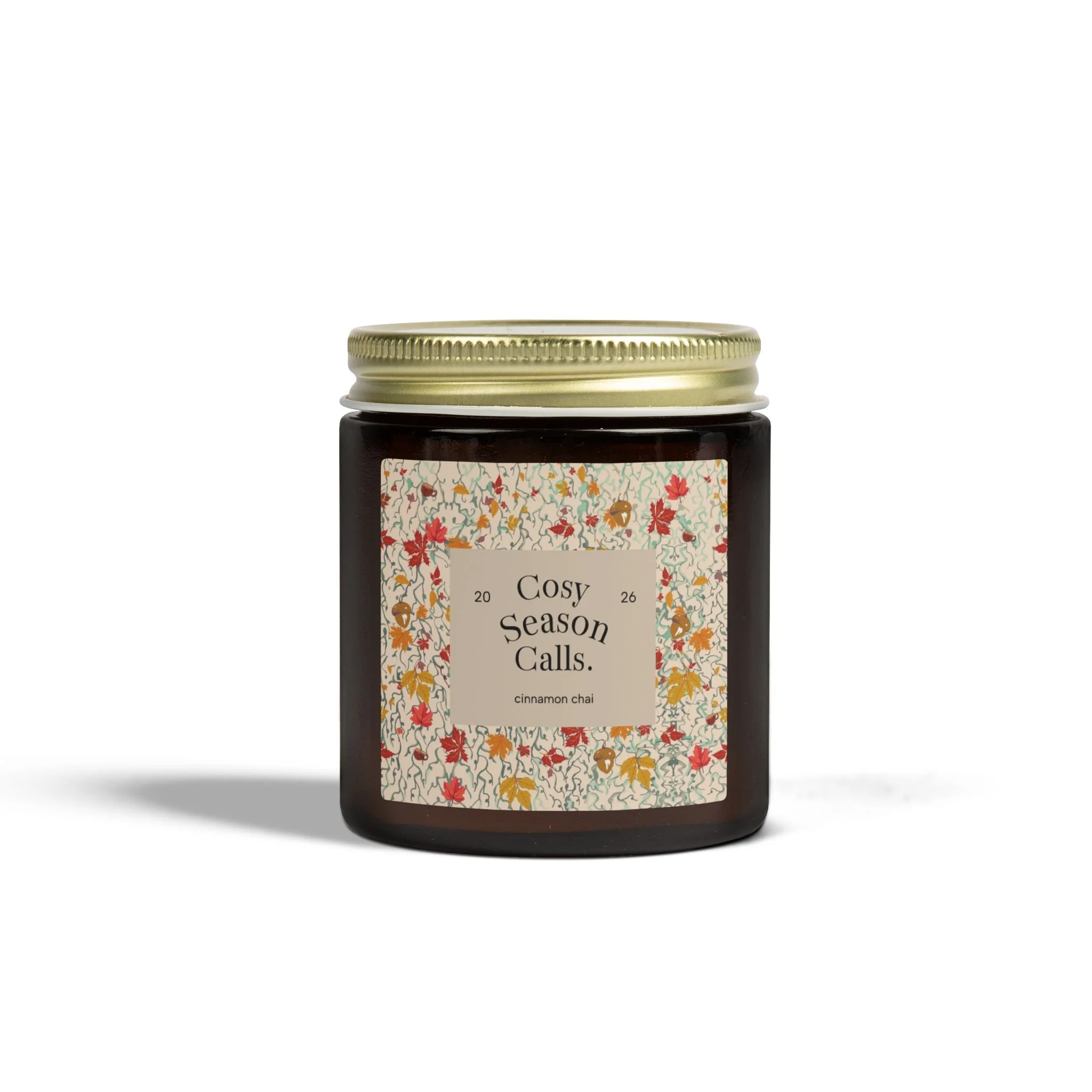Cosy Season Calls cinnamon chai scented candle in an amber glass jar with gold lid and autumn floral label
