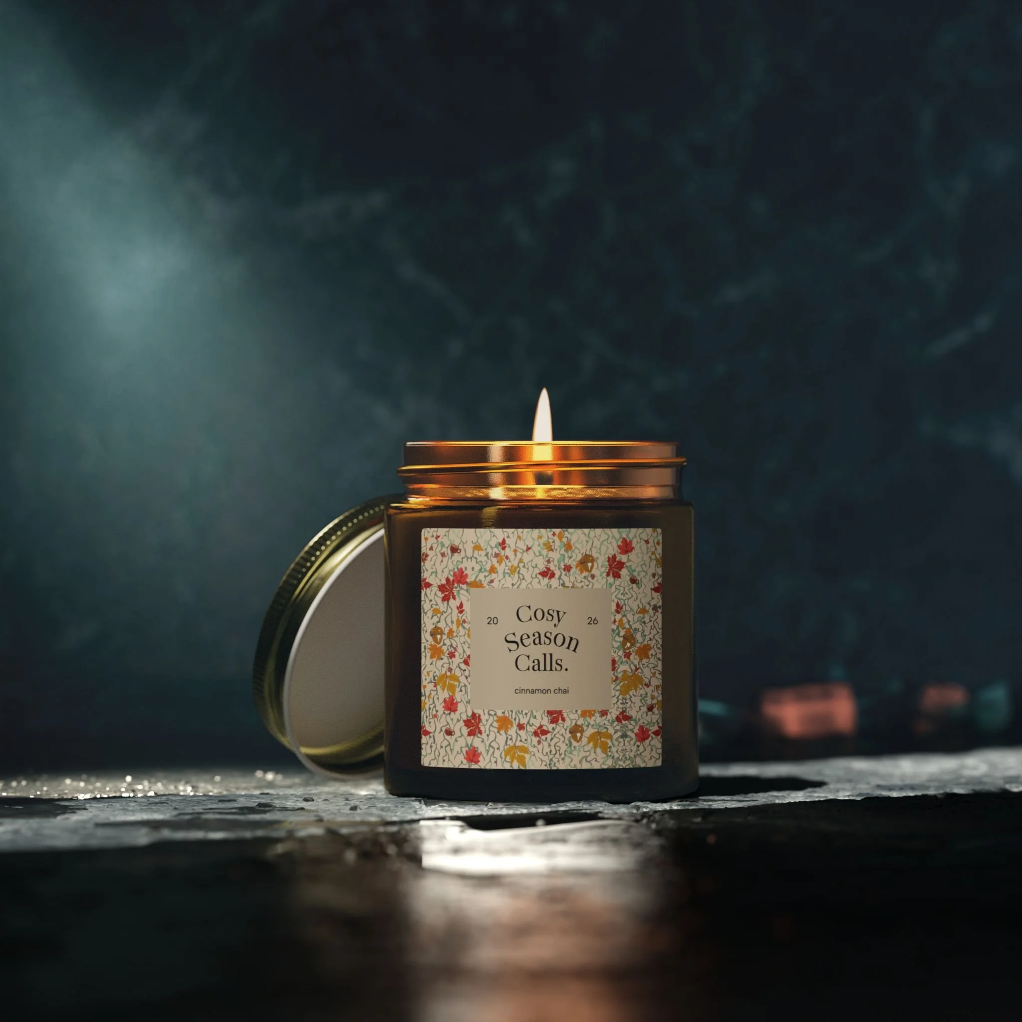 Lit cinnamon chai candle in amber glass on a dark background