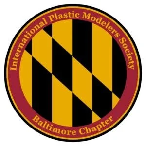 Emblem of the International Plastic Modelers Society Baltimore Chapter with black and yellow lettered shield design and maroon border