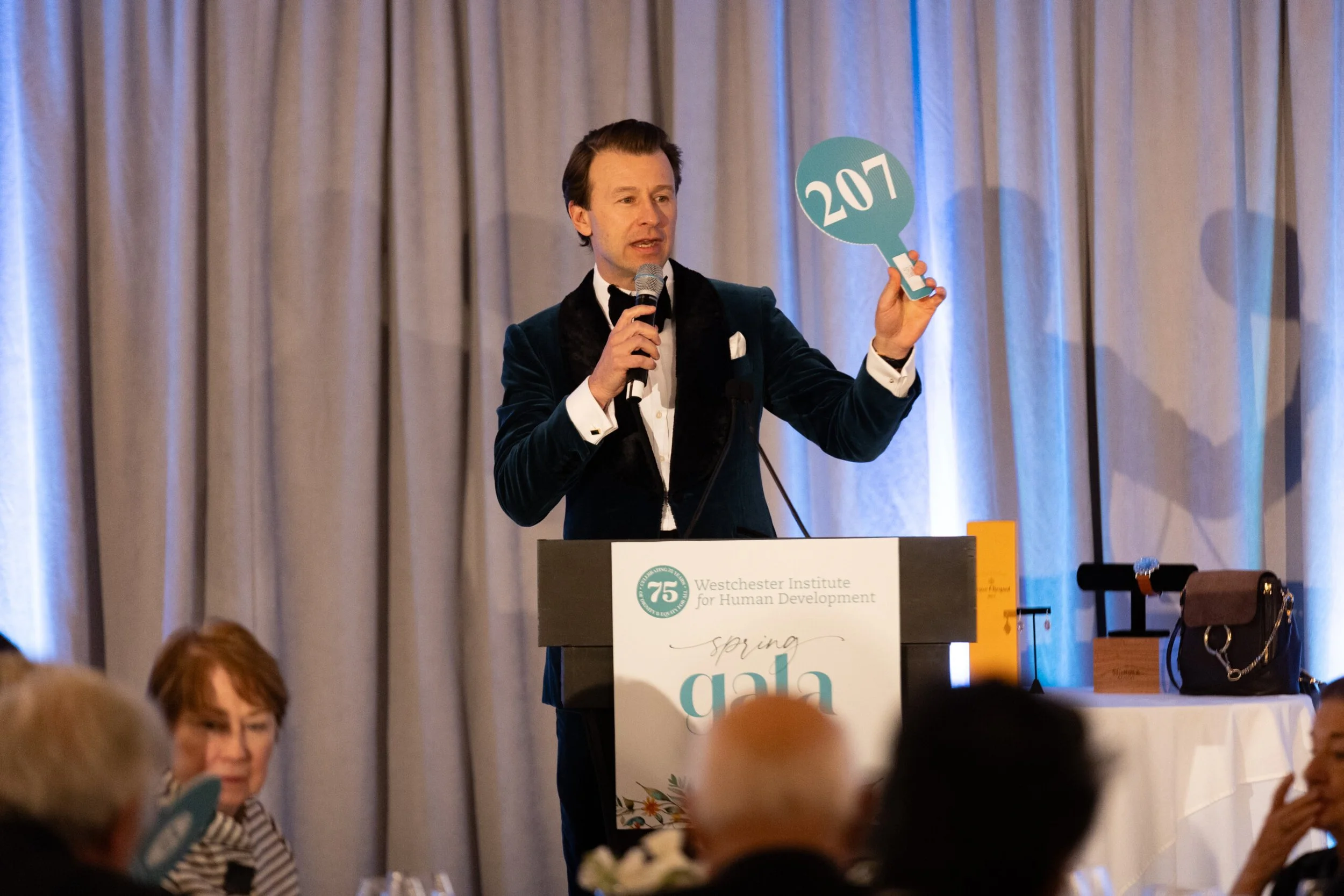 Spring gala for the Westchester Institute for Human Development where an auctioneer is raising his bidding paddle, produced by JKM Events.