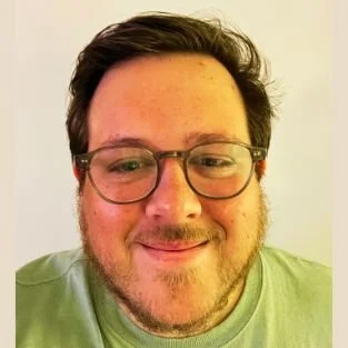 Person wearing glasses and a light green shirt smiling at the camera.