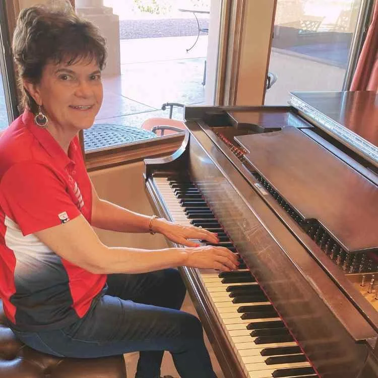 Woman playing piano by ear or improvising near large window.