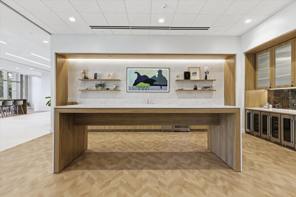Modern breakroom with a large island, wooden shelves, and a painting of a duck on the wall.