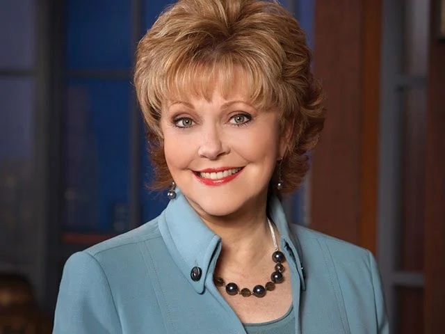 older woman short blonde hair smiling black pearl necklace blue colored shirt tv personality Terry Meeuwsen