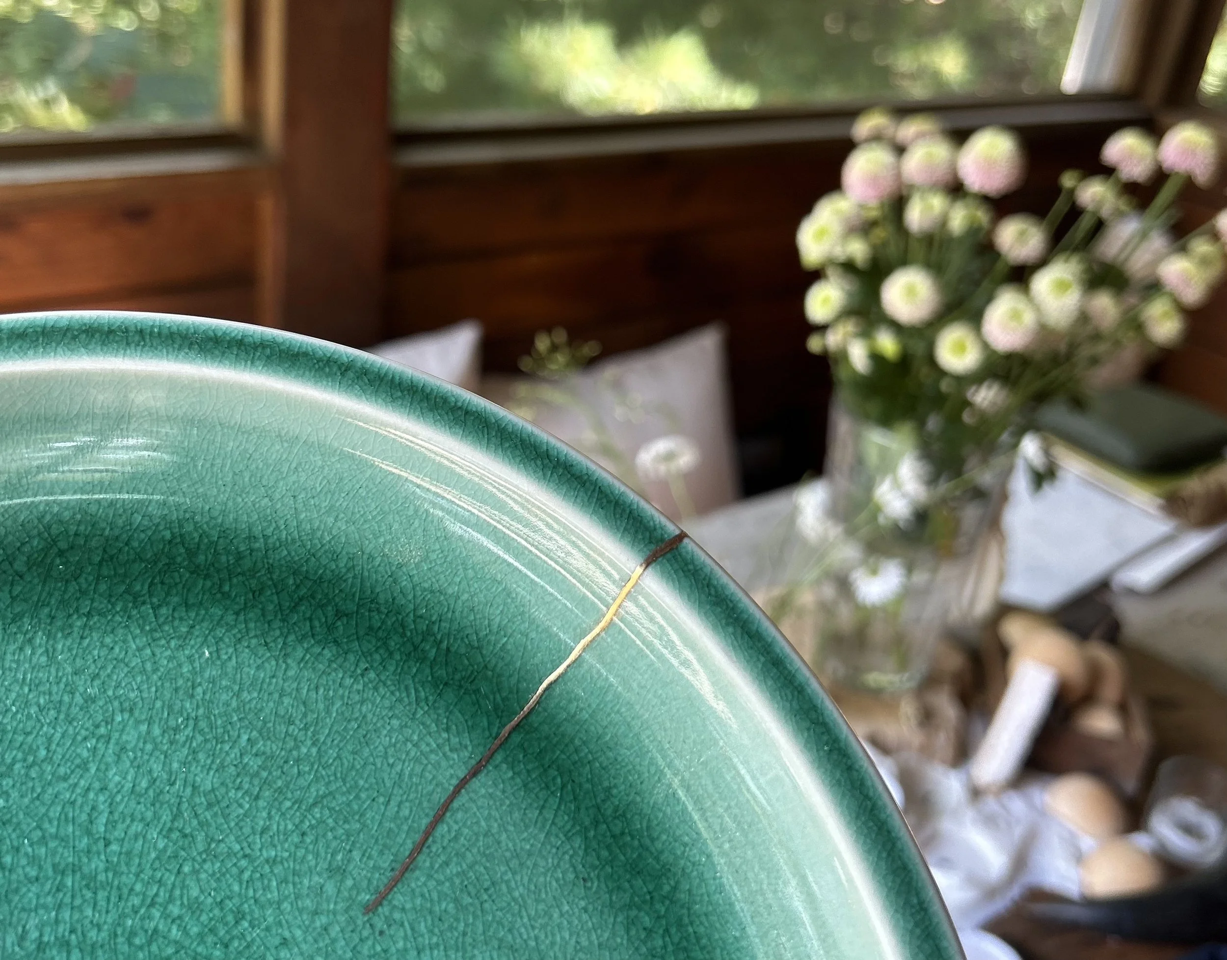 Green plate with golden kintsugi repair line on edge
