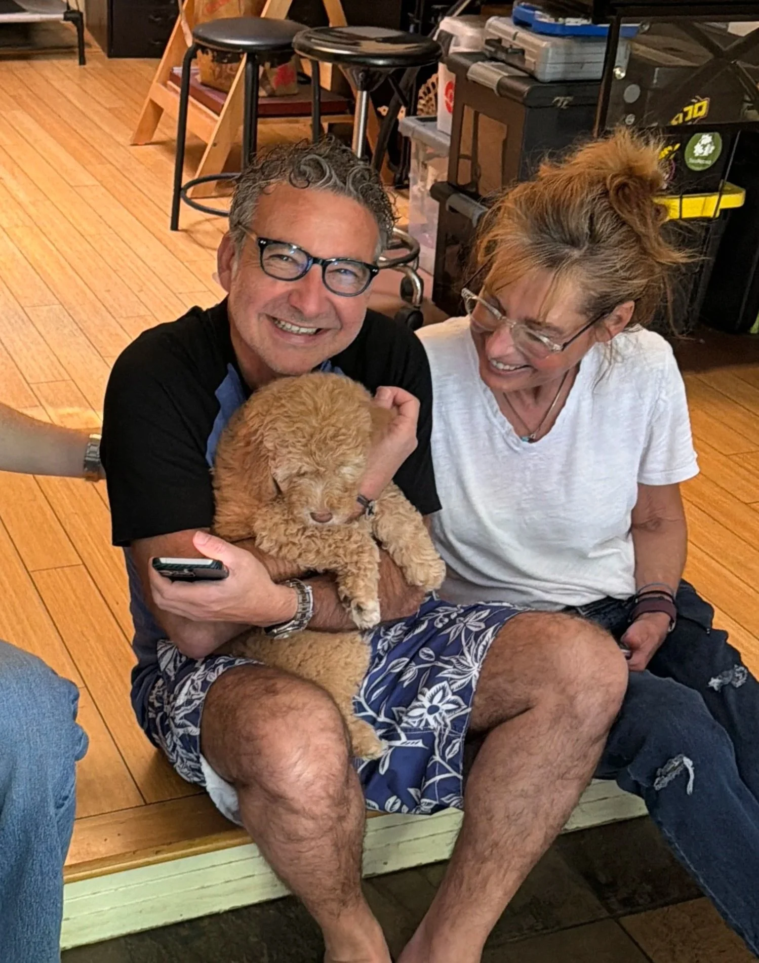 Family holding Goldendoodle puppy in their arms happy.