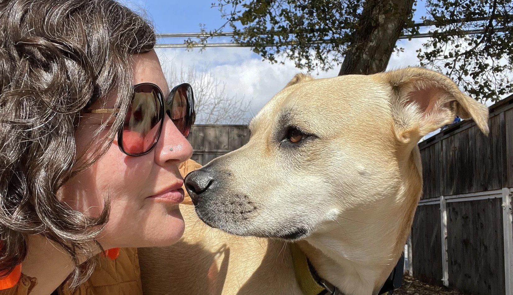 Darlene Meissner greeting a light-coloured dog outdoors.