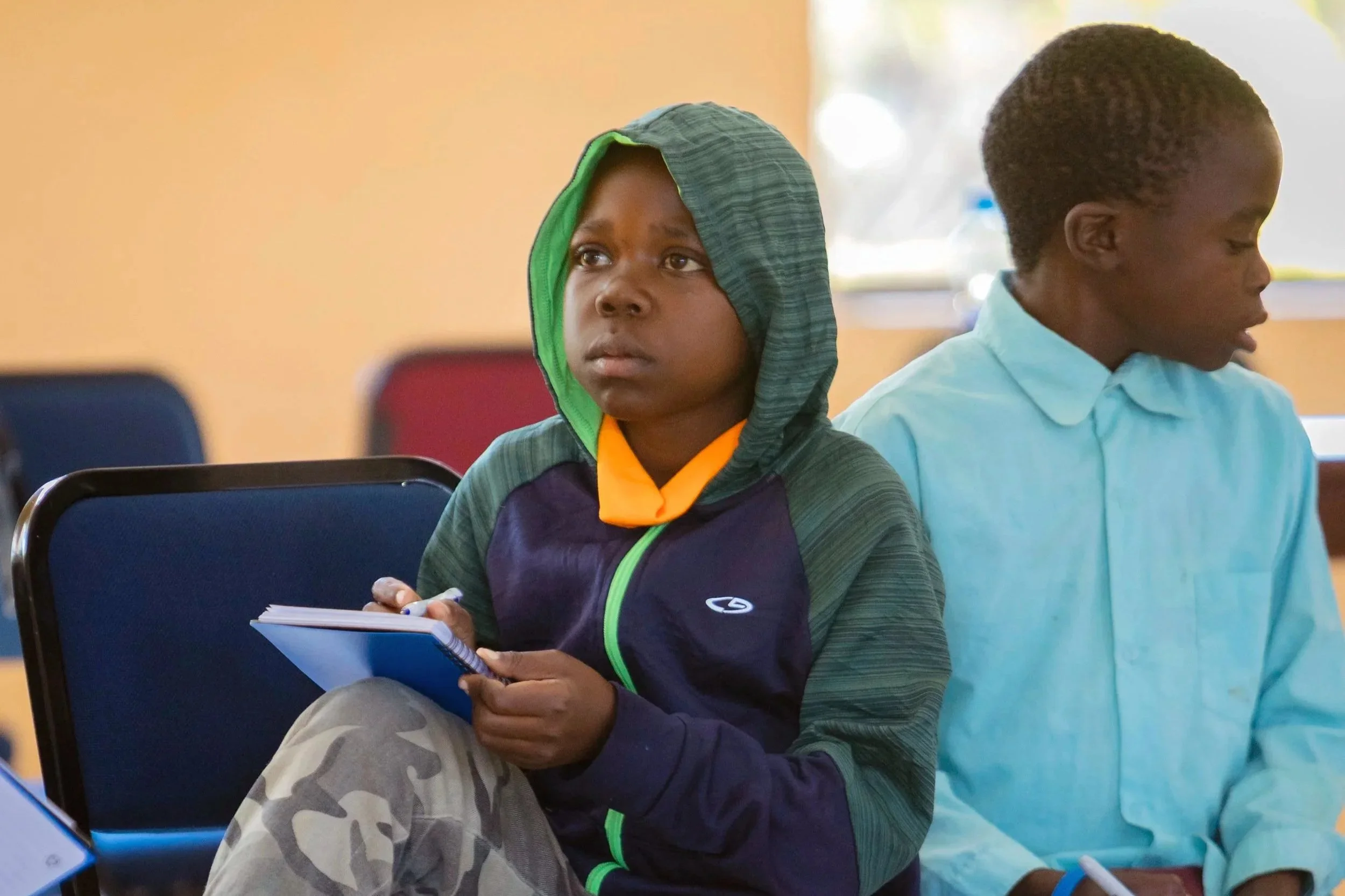  Daniel Mulowa takes notes while listening and participating during health education sessions at camp. (Photo: DOD Media Hub) 
