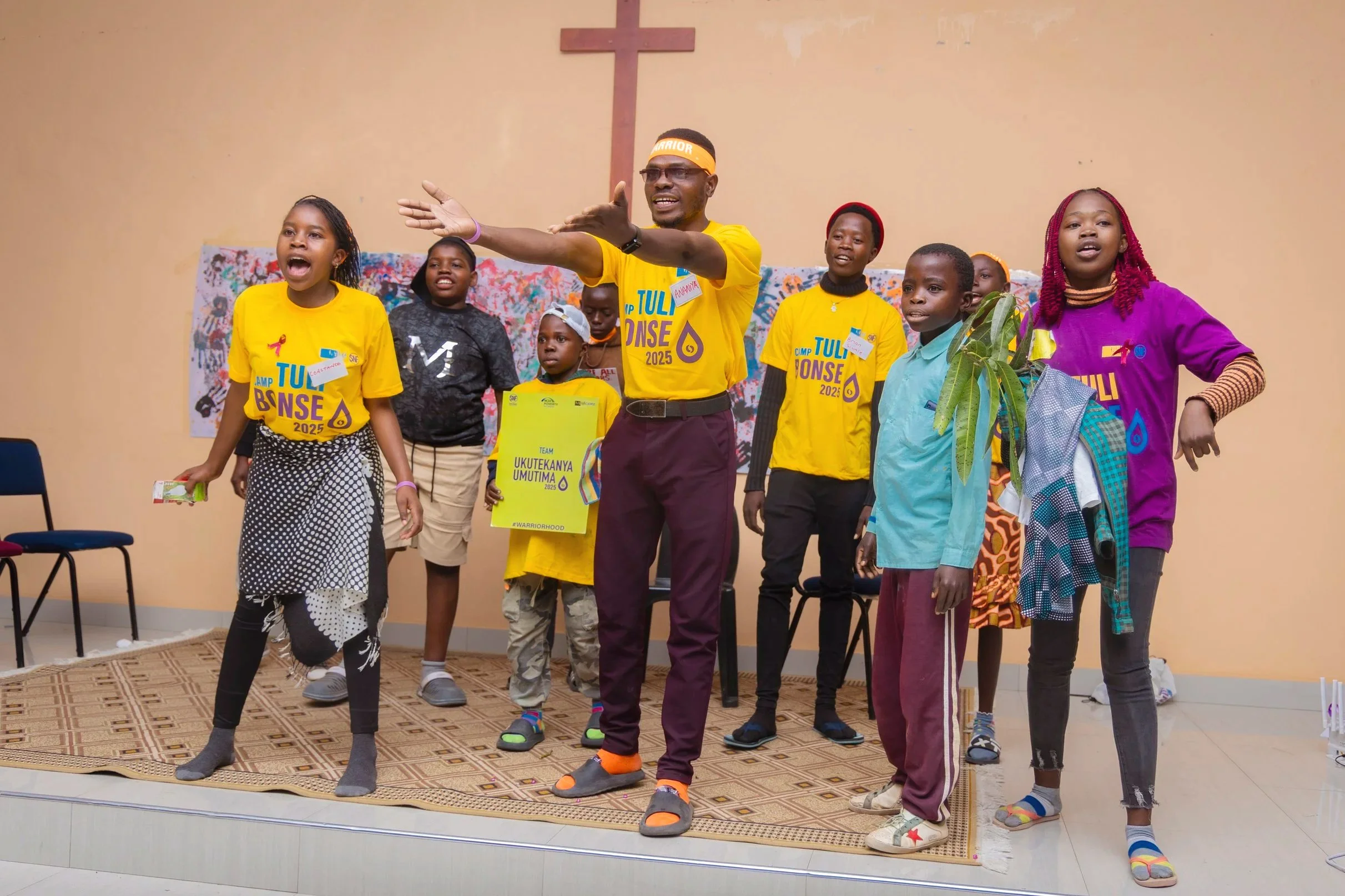  Daniel Mulowa, third from left and holding his camp team’s sign, joins his team on stage during the camp talent show. Team members acted out a skit about a sickle cell disease pain crisis, which Daniel had suffered in real life on the first night of
