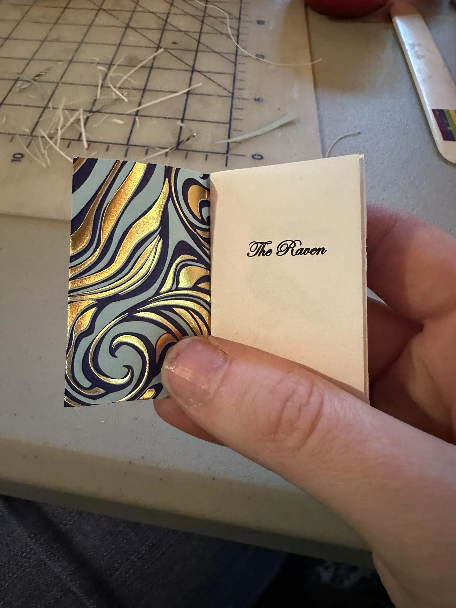 A hand holding a book that's about half the width of their thumb