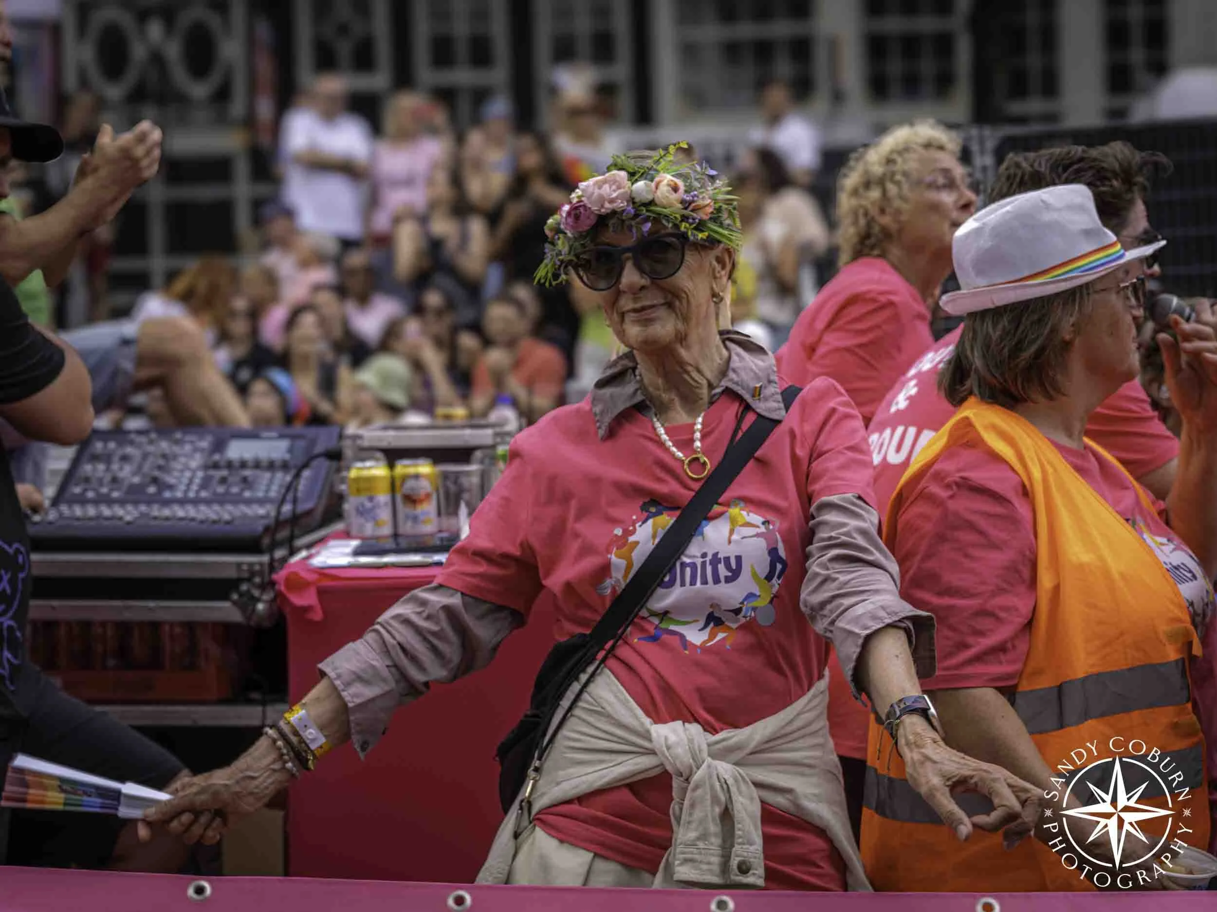 A participant similes while wearing a floral wreath at the 2026 WorldPride Amsterdam Canal Parade