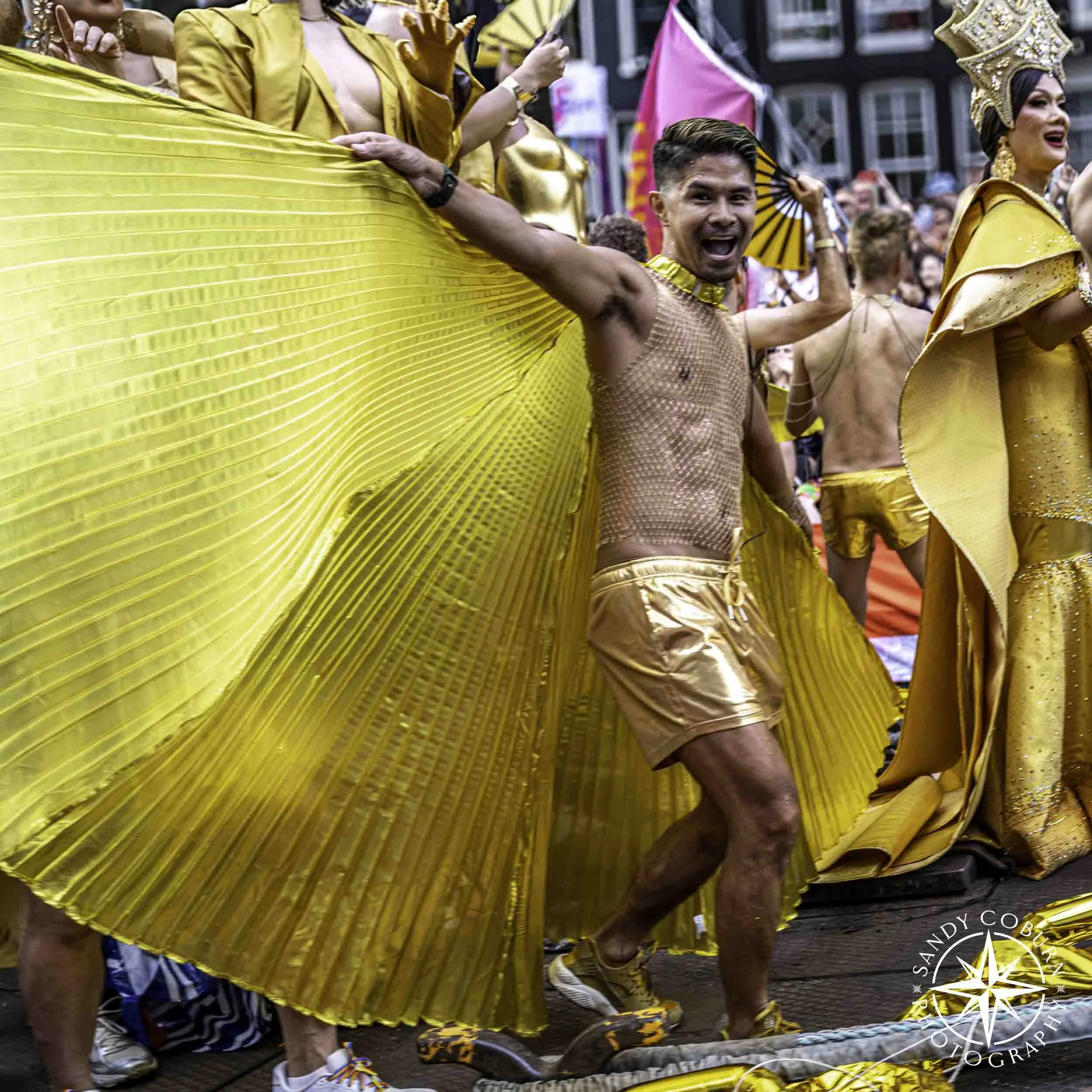 Asian Pride boat participant in a gold cape at the 2026 WorldPride Amsterdam Canal Parade