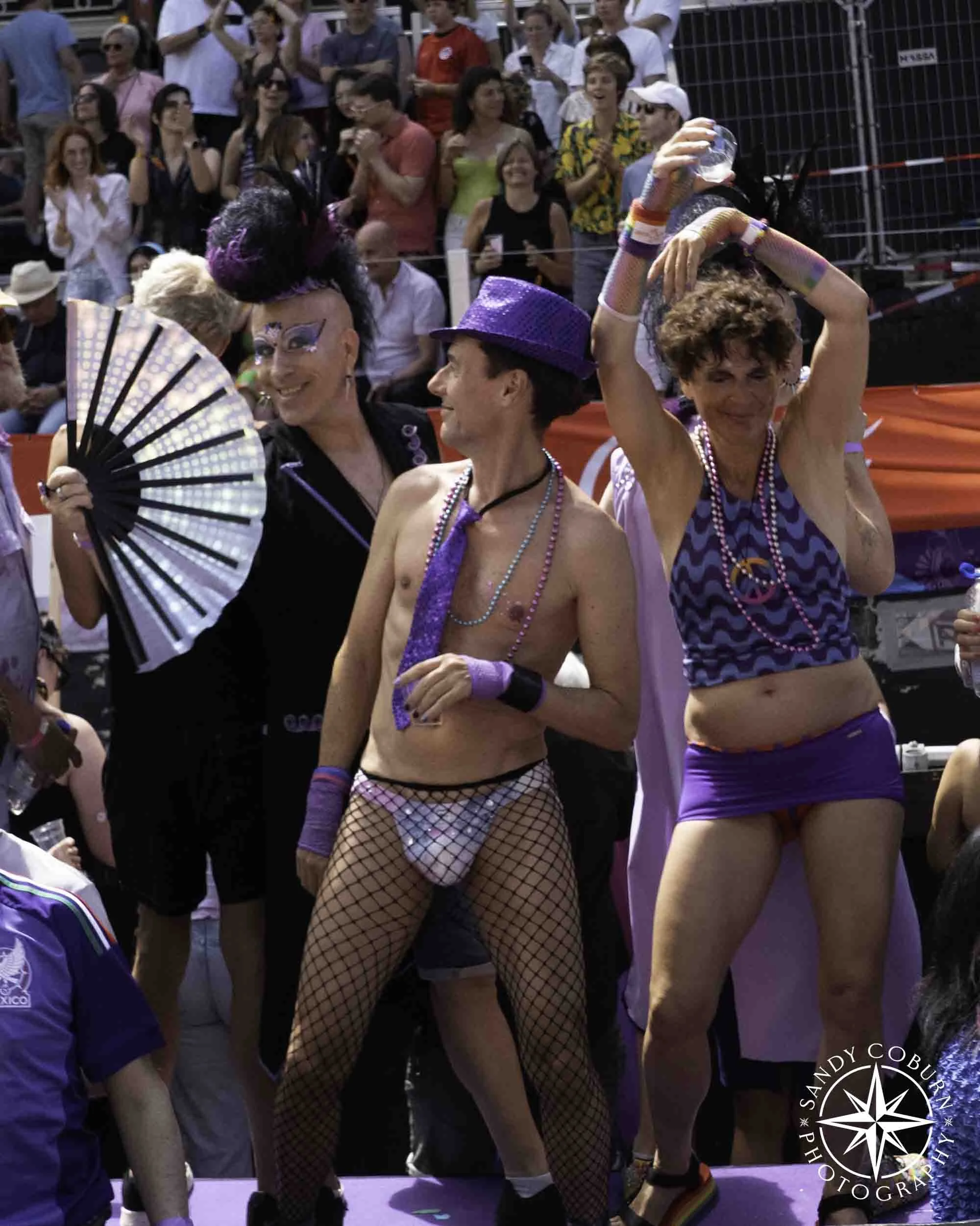 A participant fans themselves attracting an onlooker while a third person dances at the 2026 WorldPride Amsterdam Canal Parade