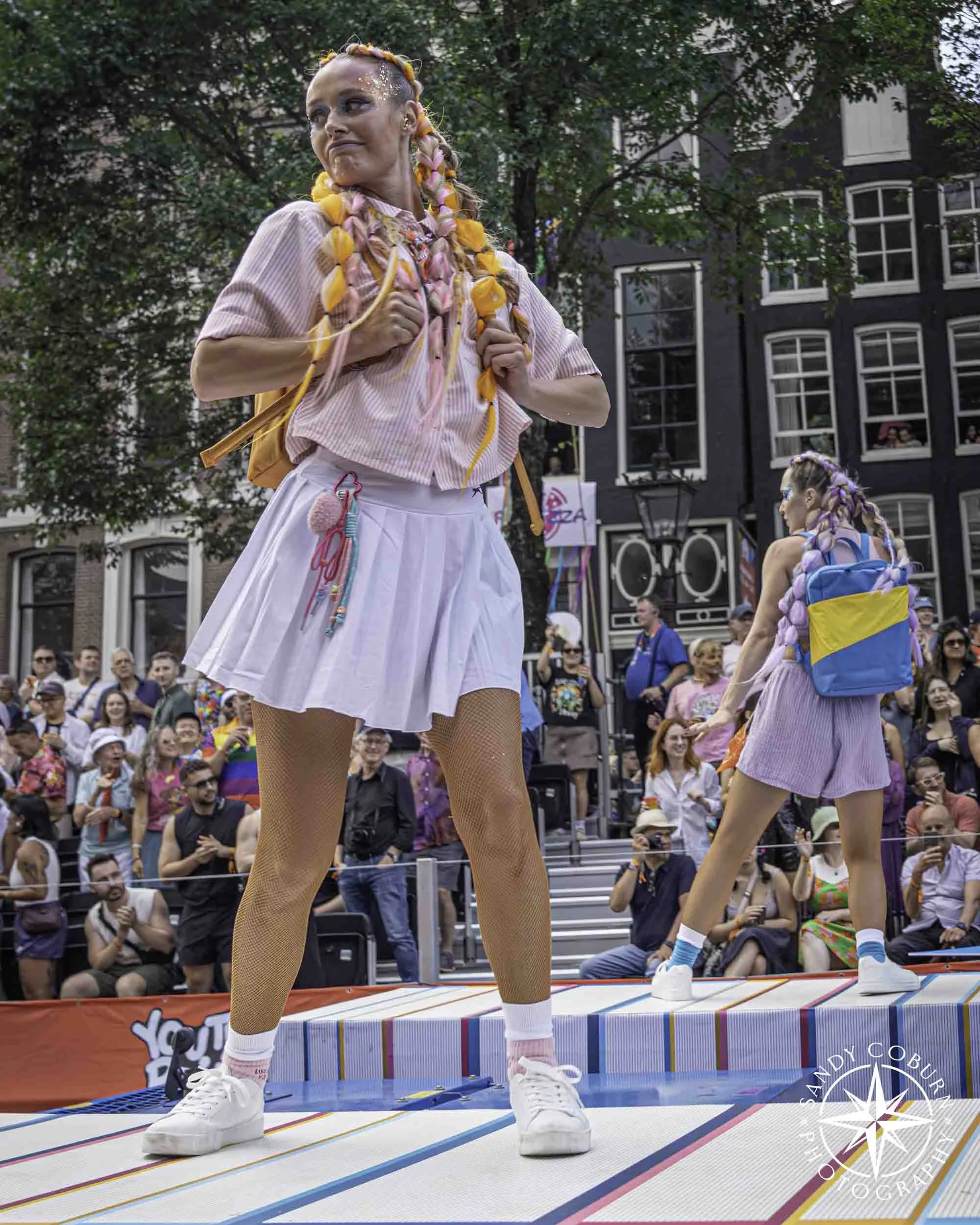 A participant poses with a backpack on the Ministry of Culture, Education, and Science (OCW) boat at the 2026 WorldPride Amsterdam Canal Parade