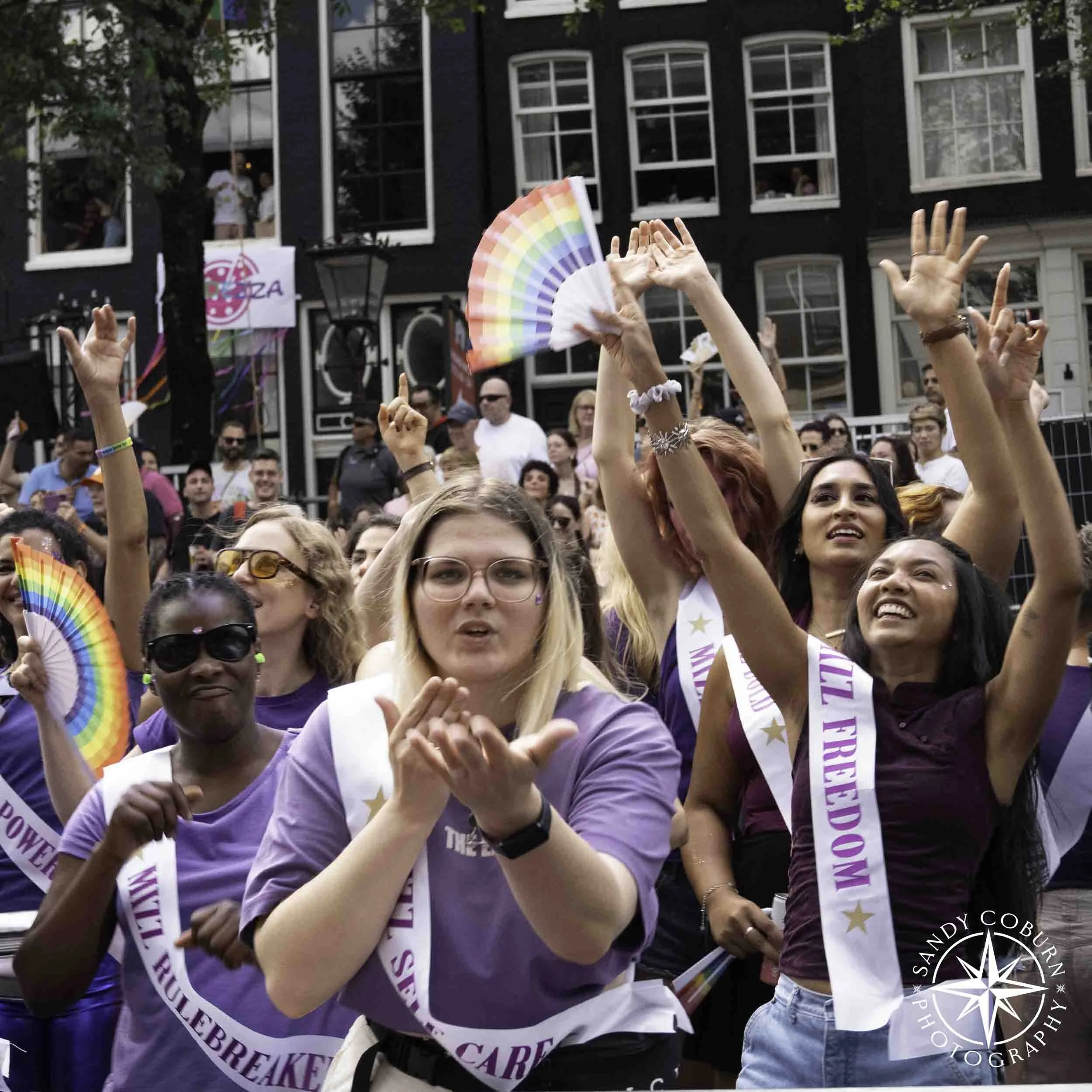 A person in purple blows a kiss to the photographer at the 2026 WorldPride Amsterdam Canal Parade