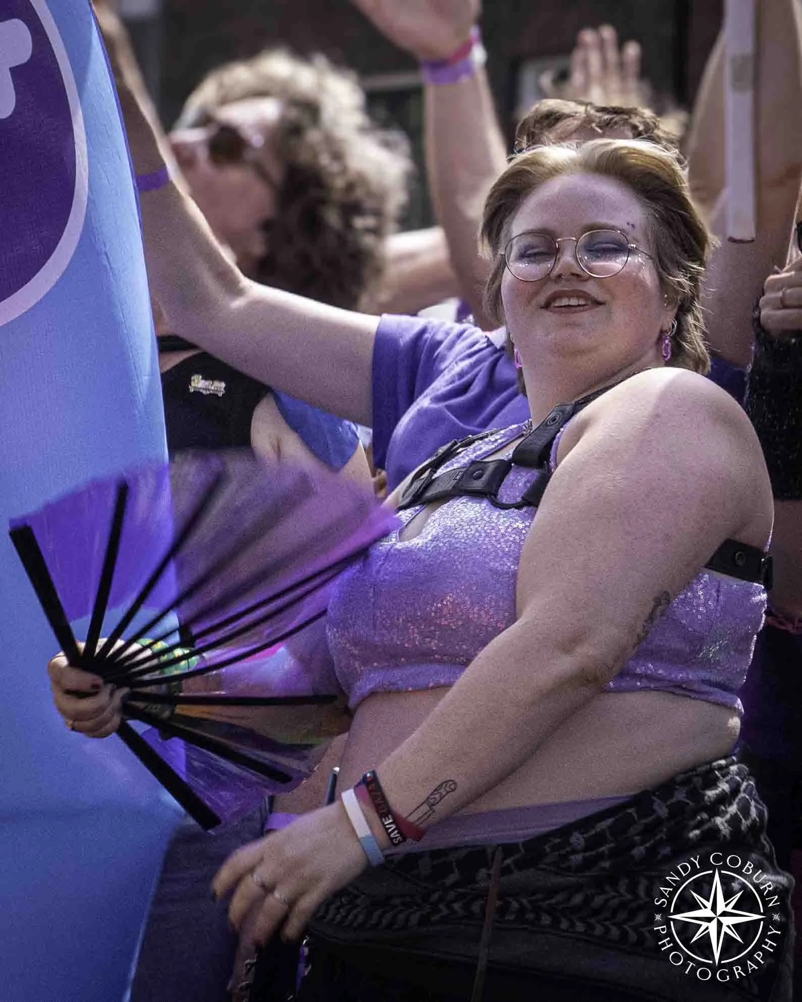 A person waves a purple fan from the bi-boat at the 2026 WorldPride Amsterdam Canal Parade