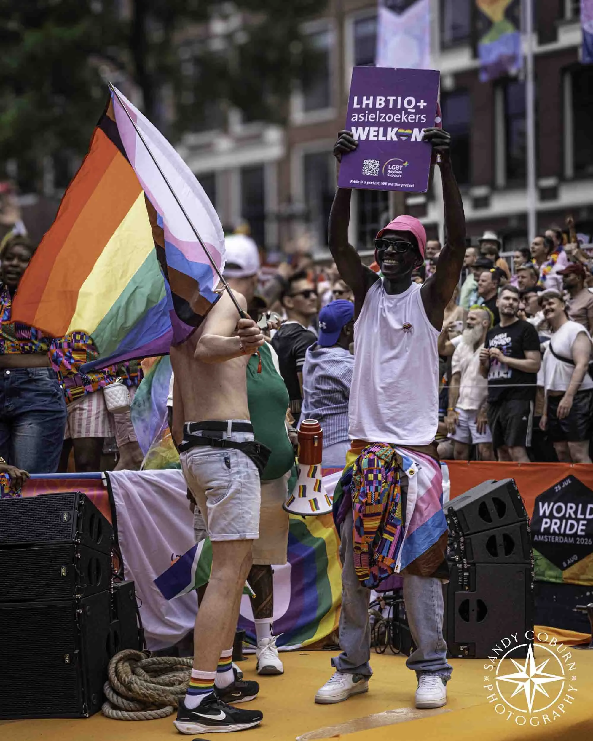 A person holds a sign in support of LGBTQIA+ assylum seekers at the 2026 WorldPride Amsterdam Canal Parade