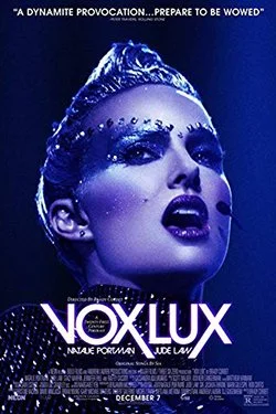 Close-up of a performer with dramatic makeup and a hair bun, promotional poster for 'Nox Lux' showcasing a futuristic theme.