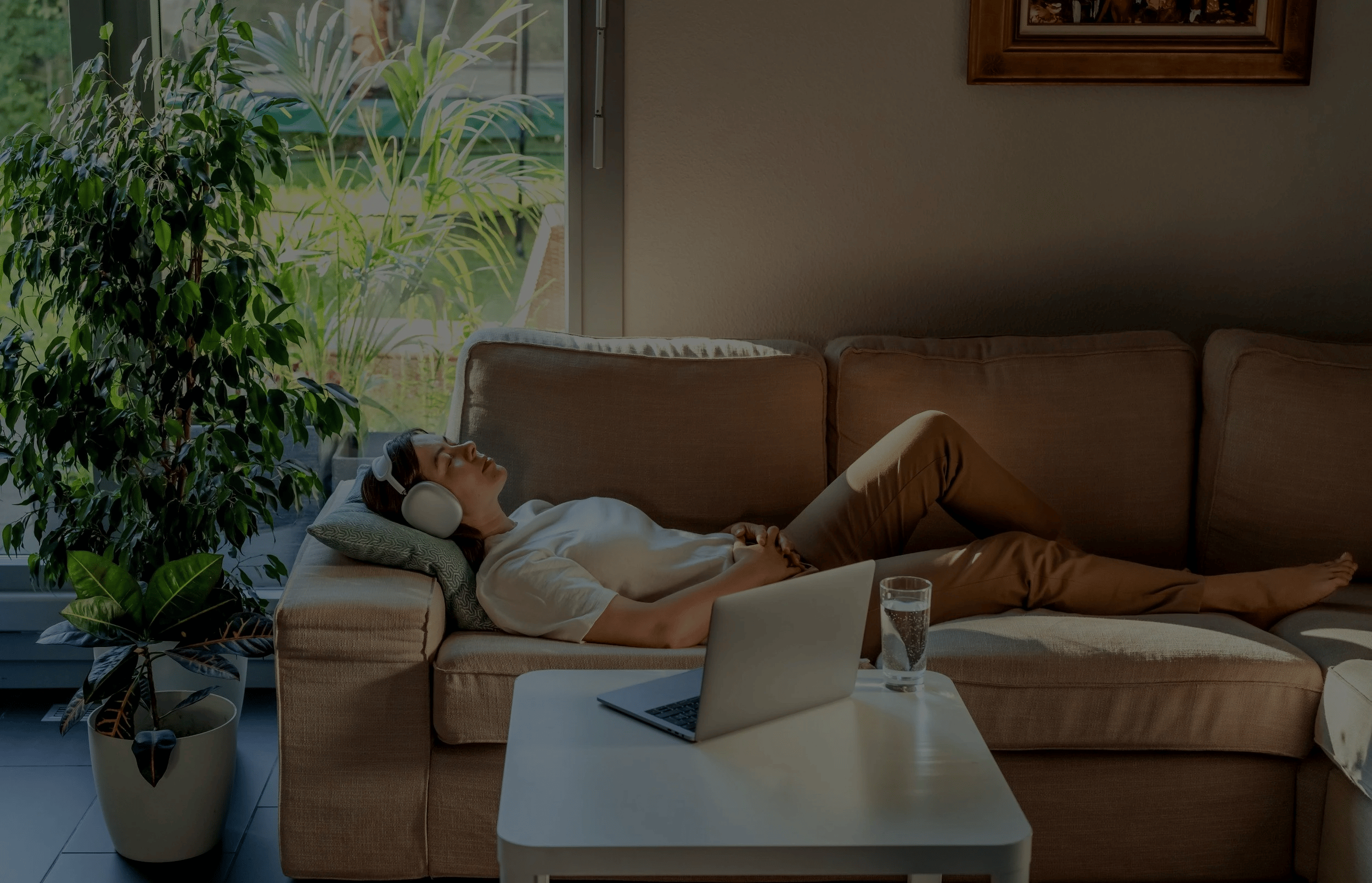 interior of Chariot Spaces psilocybin service center featuring a warm, well-lit room with lush houseplants on wooden shelves and window sills, comfortable seating, decorative curtains, and a wall art piece.