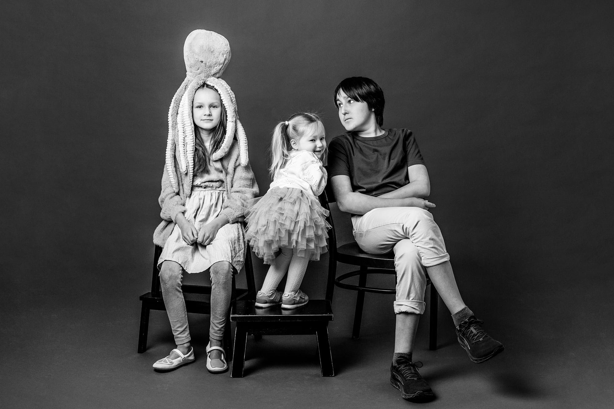 Black and white studio portrait of three siblings seated together, captured by Smallish, a Seattle children's photographer.